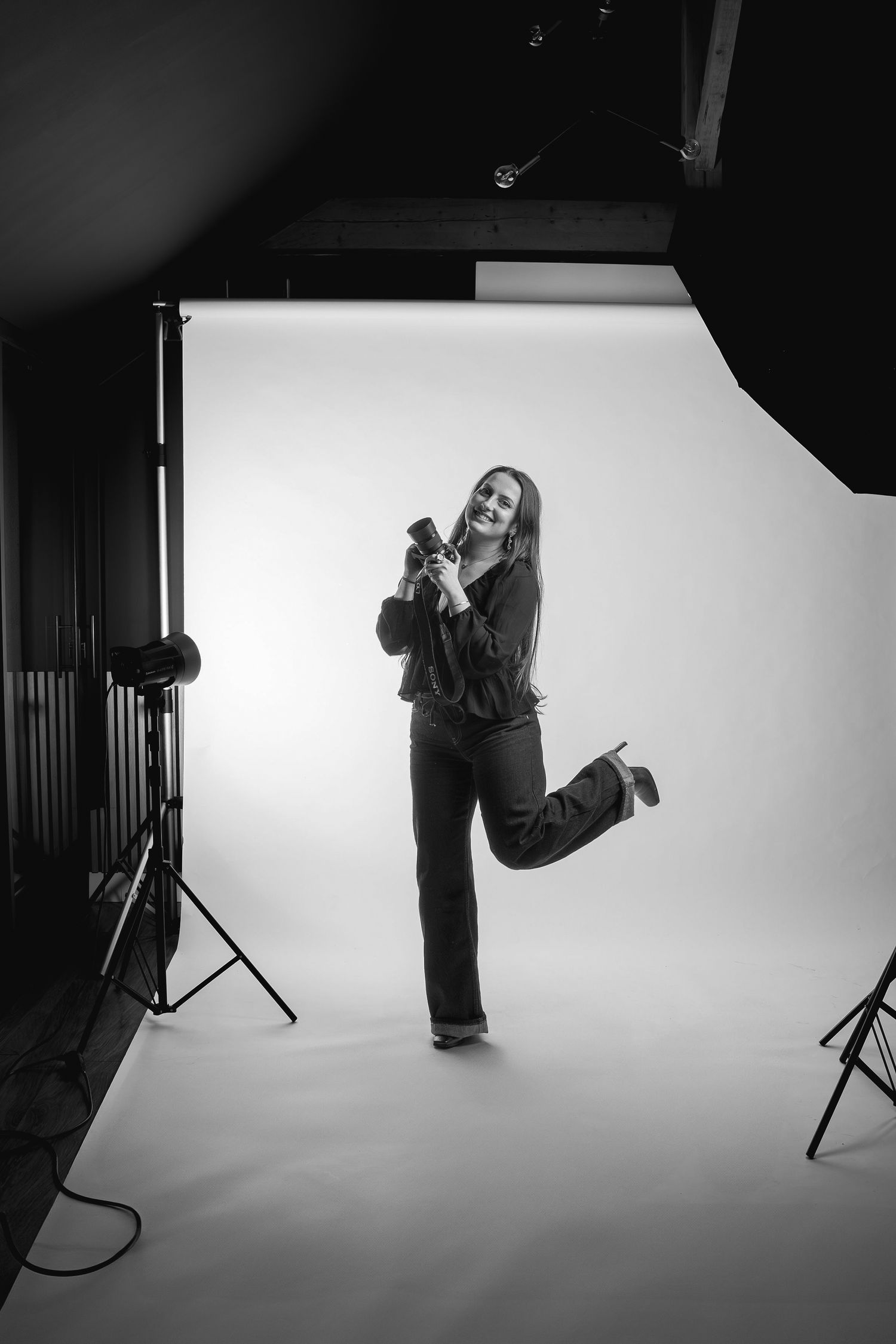 Energetic photographer jumping while taking pictures in professional studio setting.