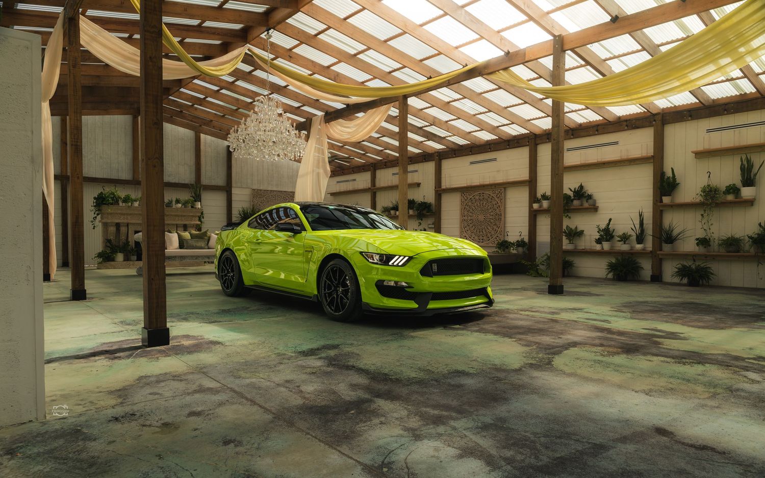 A bright neon green sports car parked in an industrial warehouse space with skylights and concrete floors.