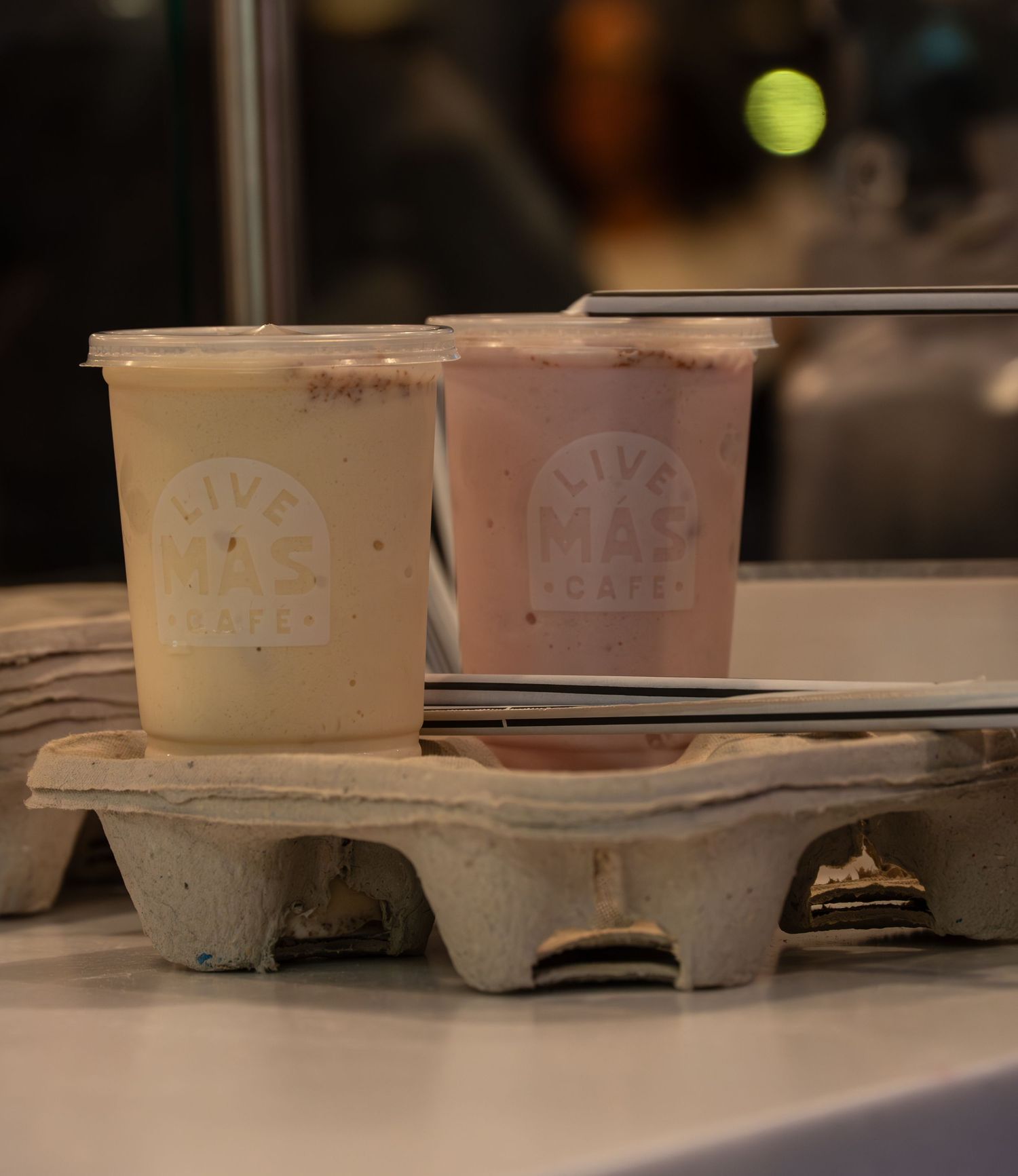 Two Live Mas Cafe branded drinks in a cardboard carrier on a counter.