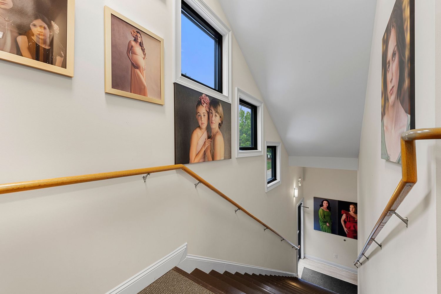 Staircase hallway gallery wall featuring professional portrait photography prints on white walls.