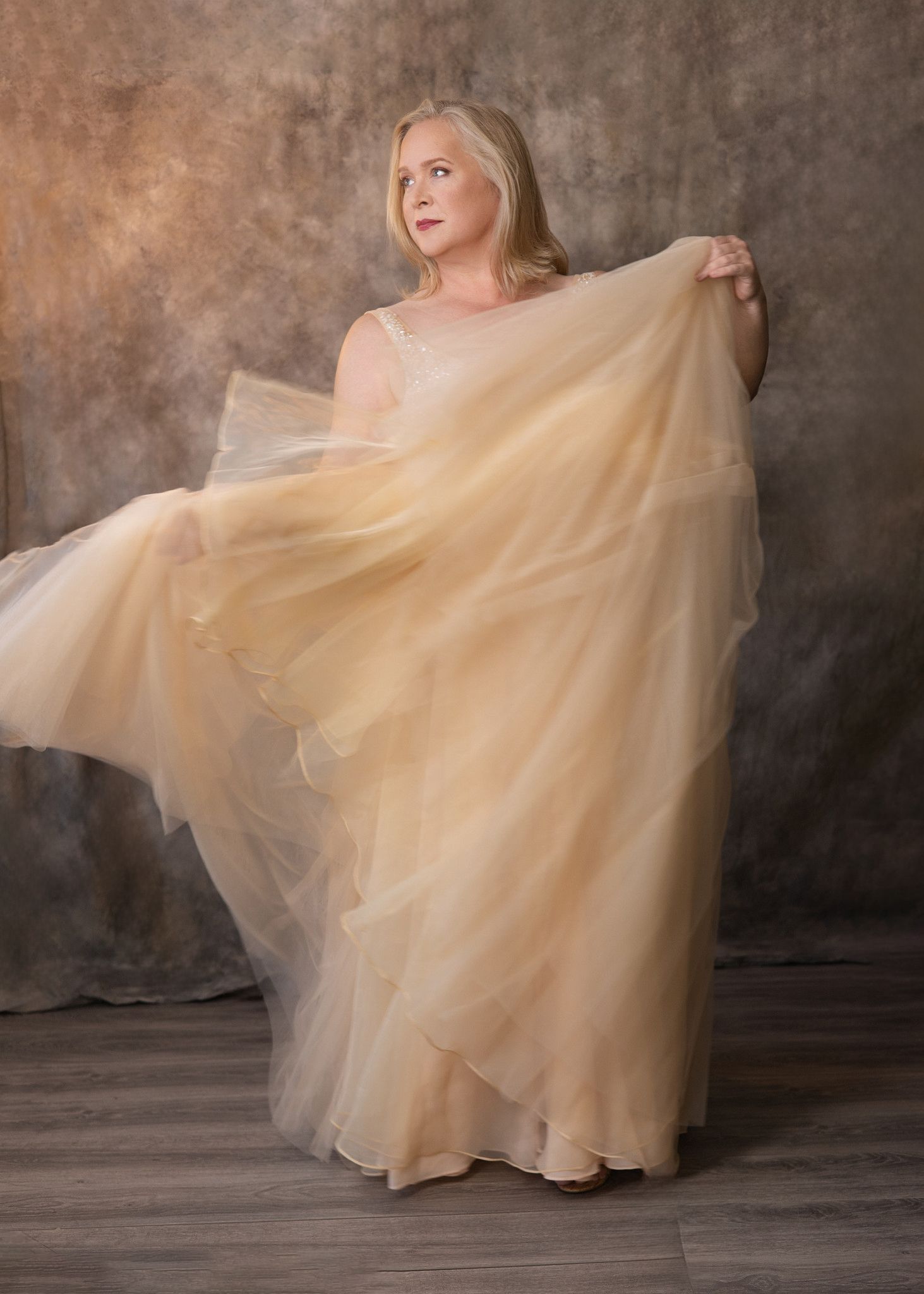 Woman in golden tulle gown, dreamy studio portrait
