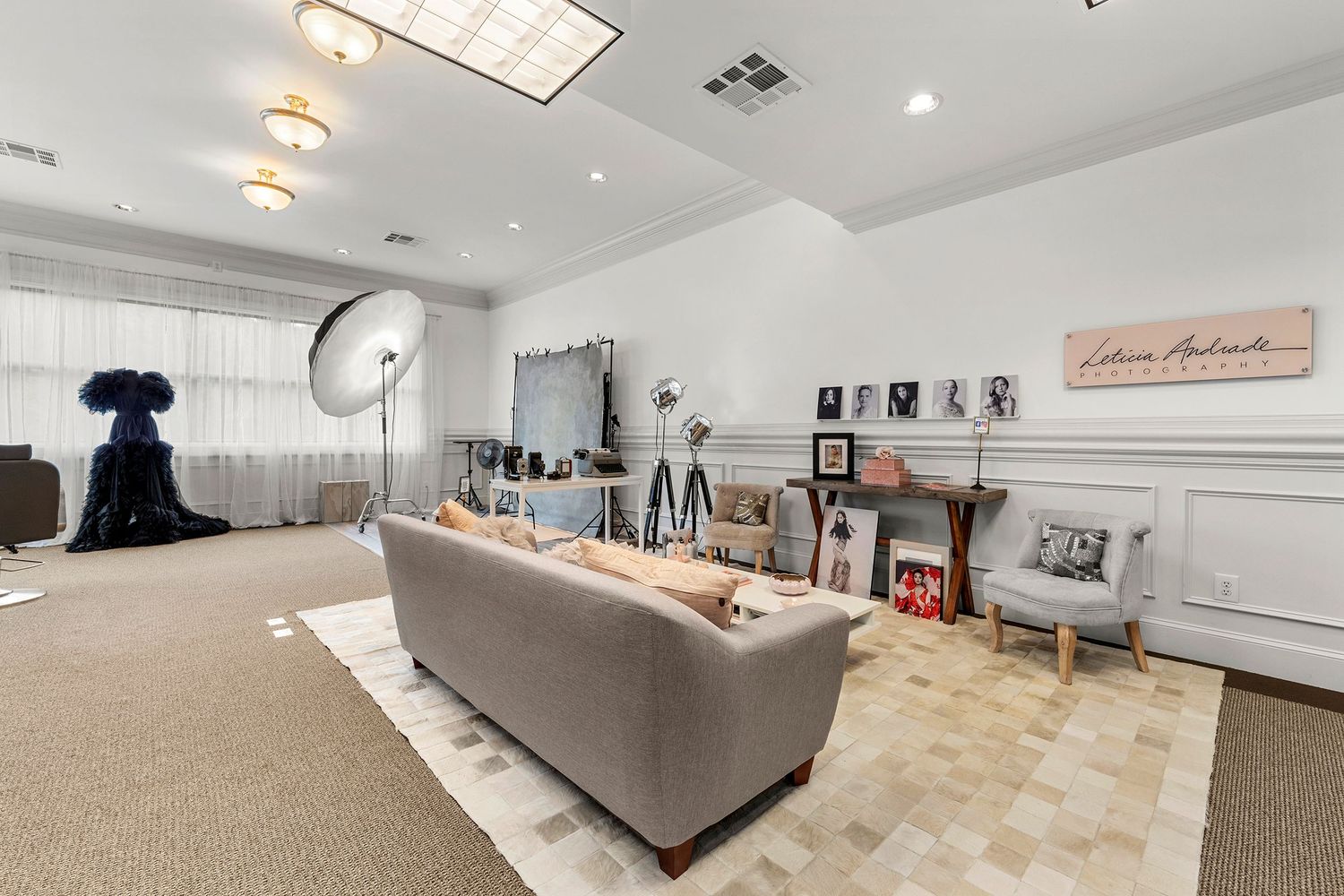 Bright photography studio with gray sofa, professional lighting equipment, and fireplace mantel.