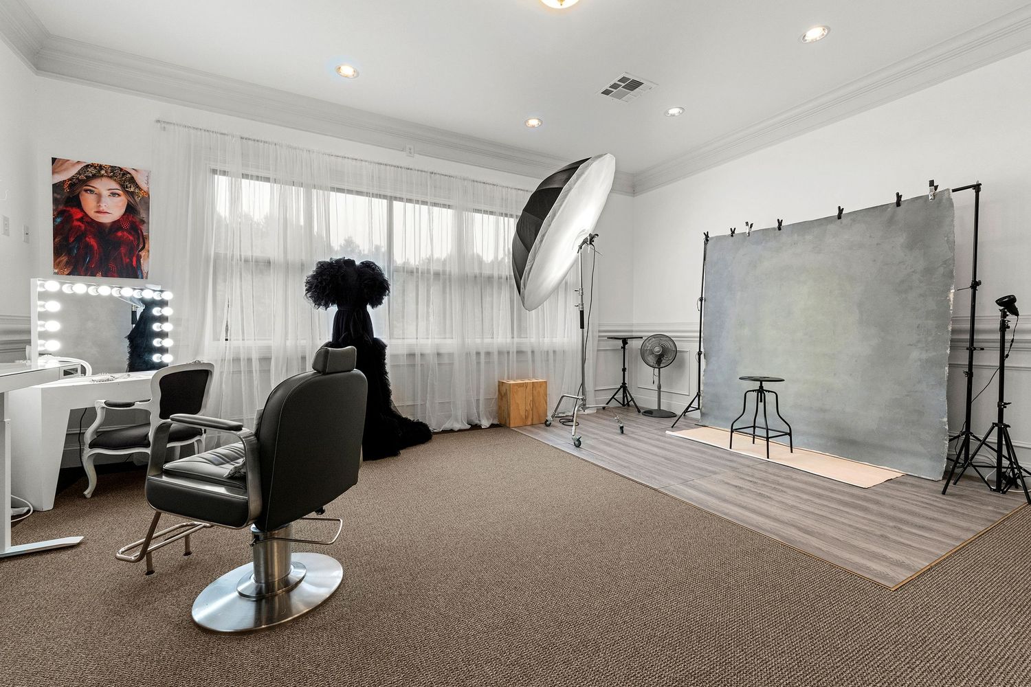 Professional photo studio with backdrop, strobe lighting, barber chair, and Hollywood vanity mirror.