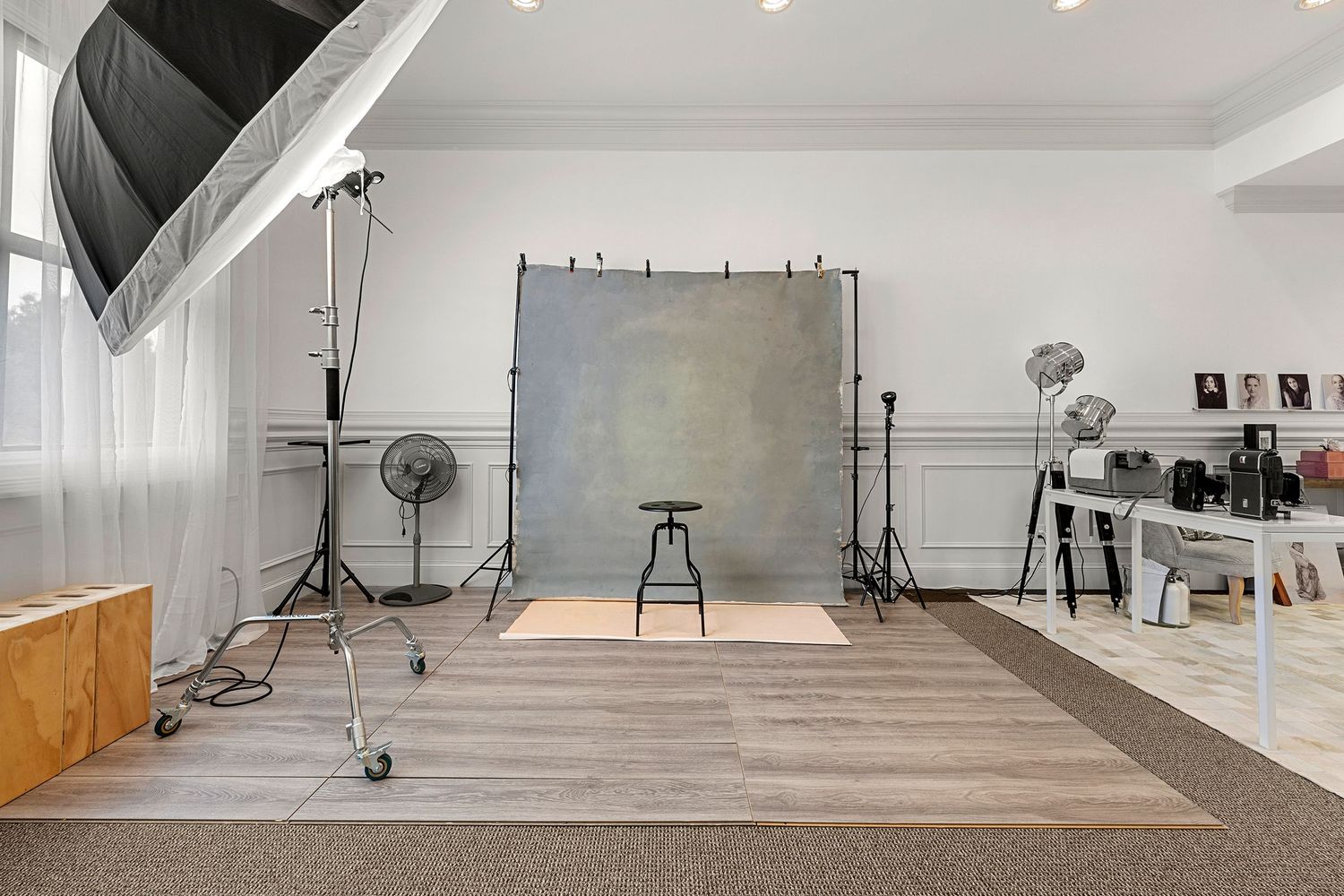 Professional photography studio with gray backdrop, lighting equipment, and hardwood floors.