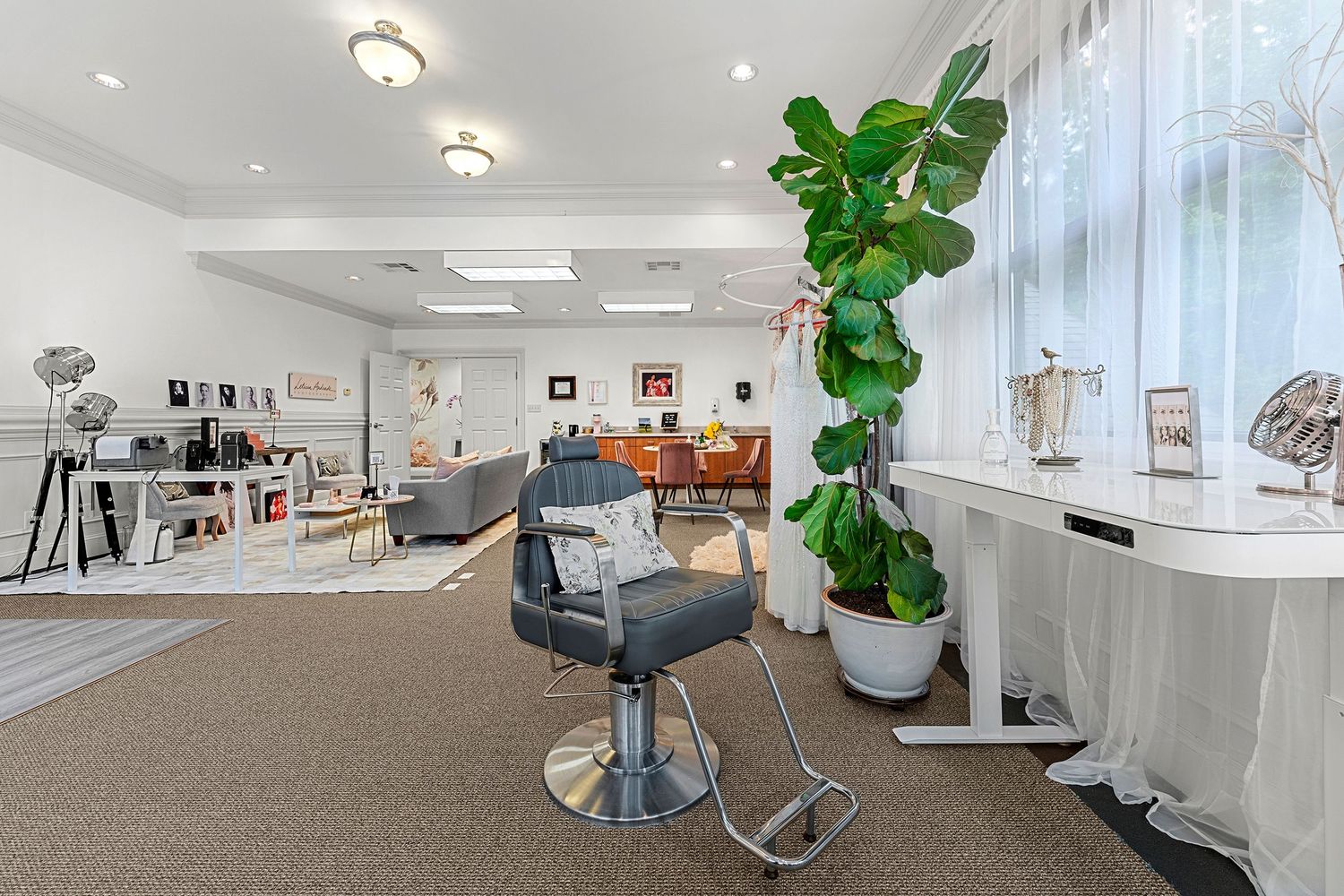 Spacious photography studio with barber chair, fiddle leaf fig tree, and open lounge area.
