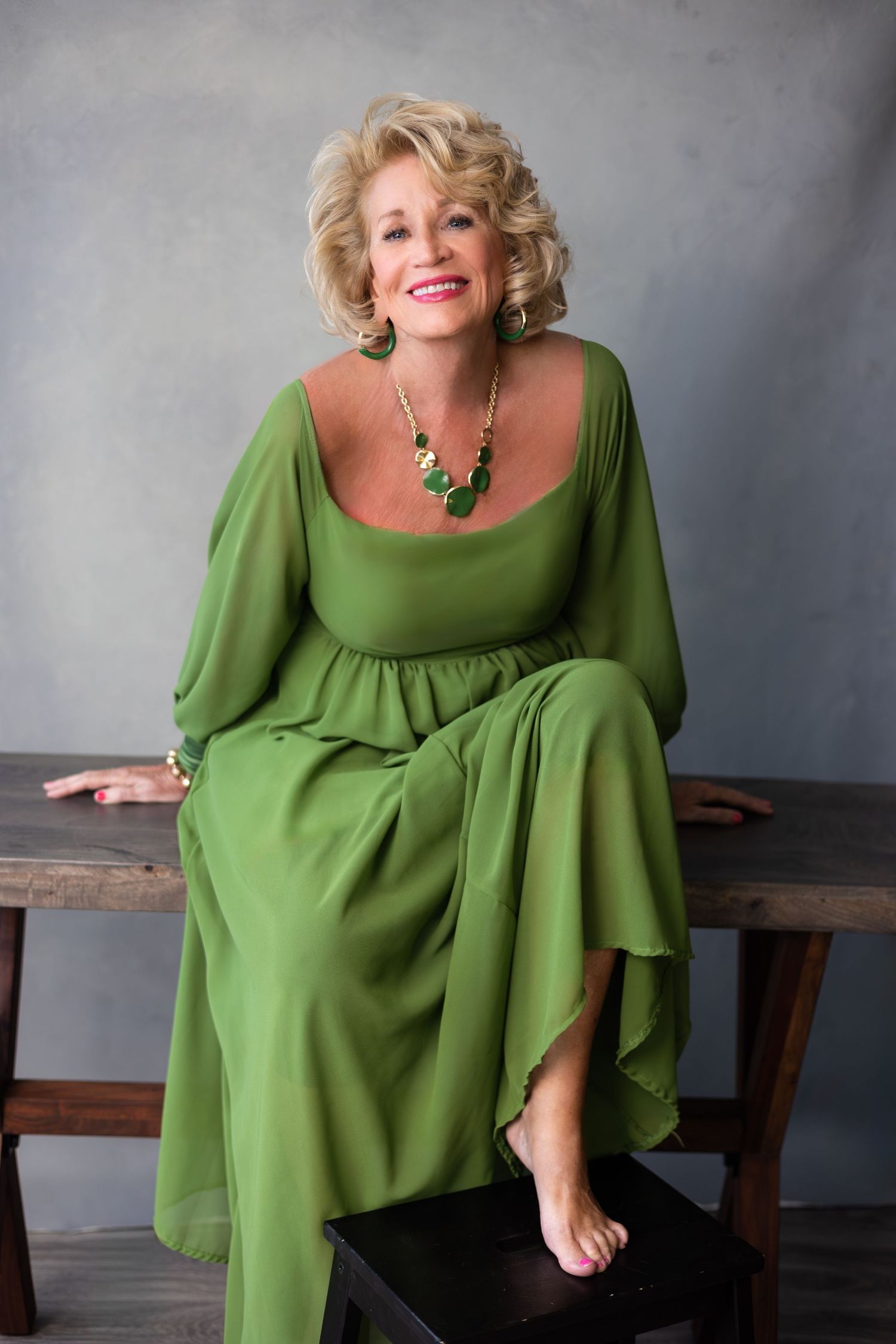 Smiling woman in green flowing dress, studio portrait