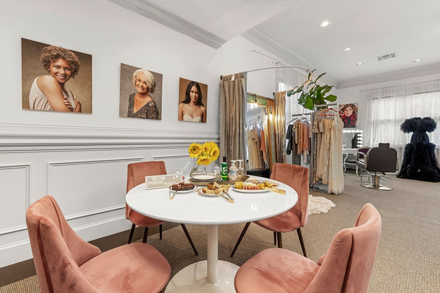 Chic dining nook with round white table, pink velvet chairs, and celebrity portrait wall art.