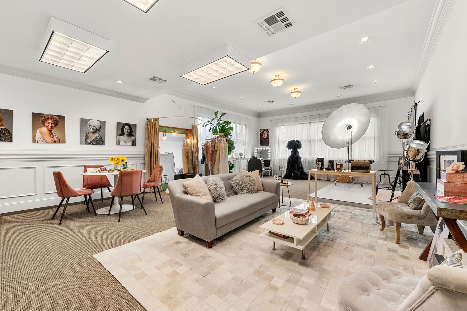 Stylish photography studio lounge with gray sofa, ring light, wainscoting, and clothing rack.