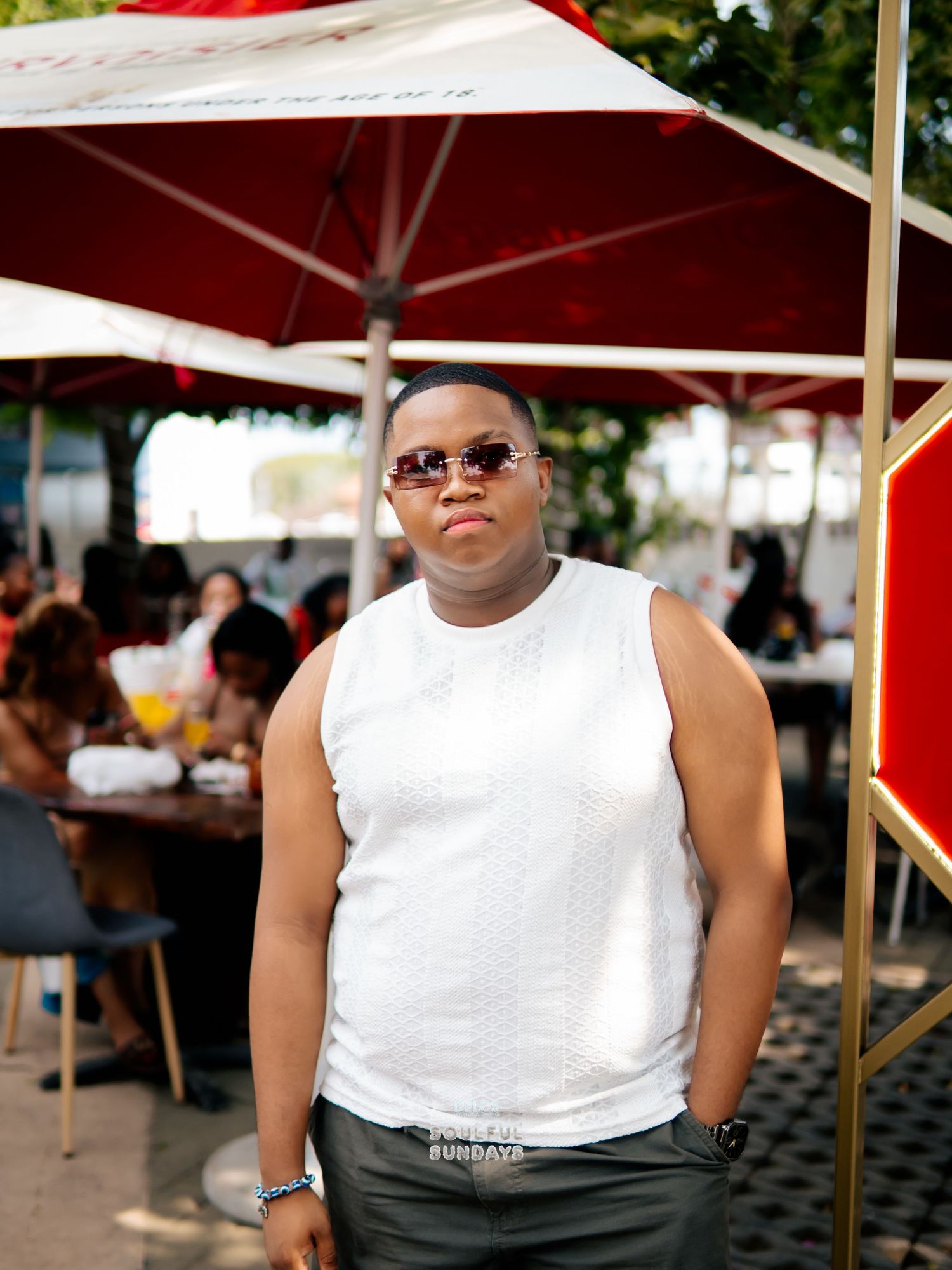 Person in white sleeveless top and sunglasses standing at an outdoor restaurant patio event.