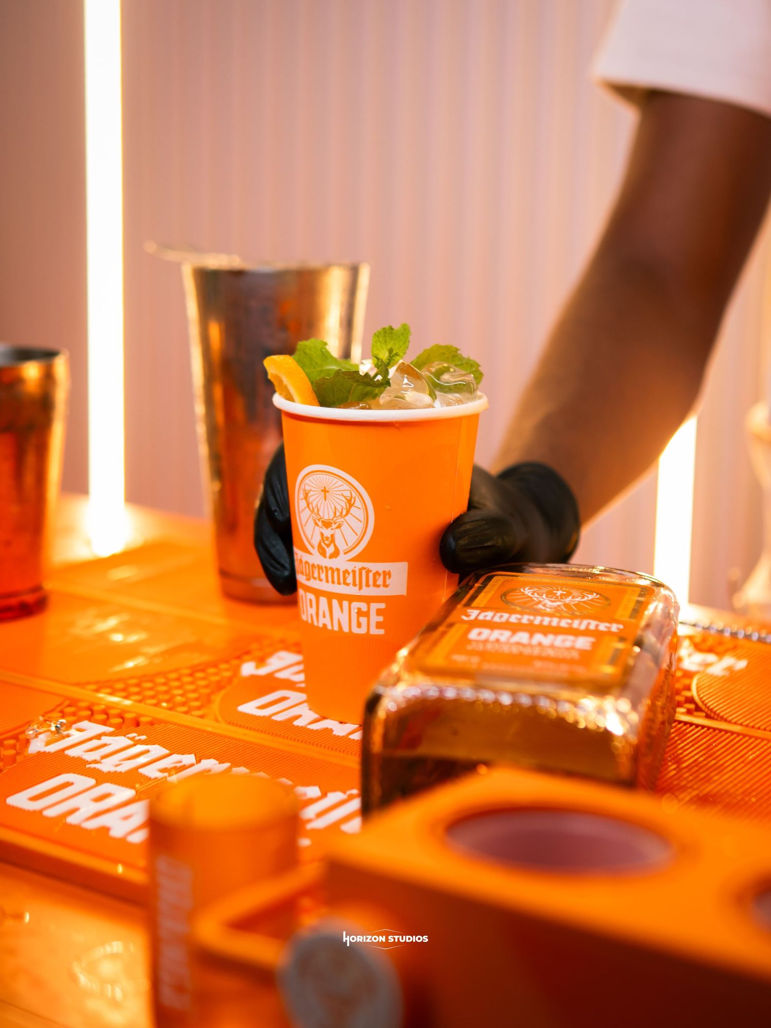 Jagermeister Orange cocktail in branded cup with mint garnish on orange branded bar setup.