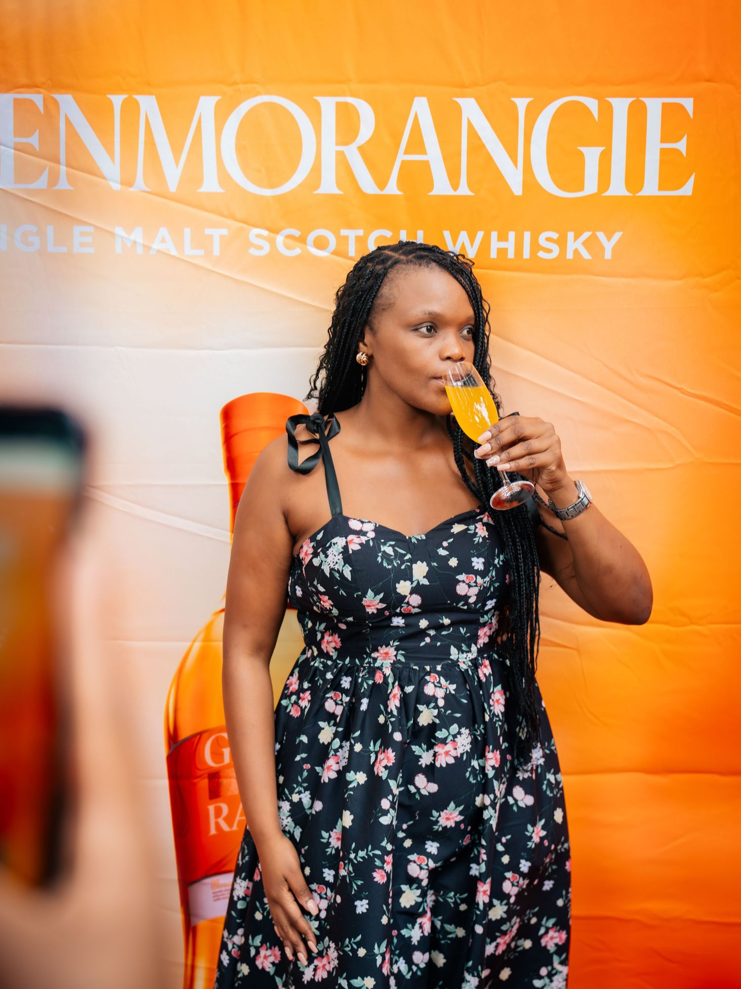 Woman in floral dress sipping whisky at Glenmorangie Single Malt Scotch Whisky promotional event.