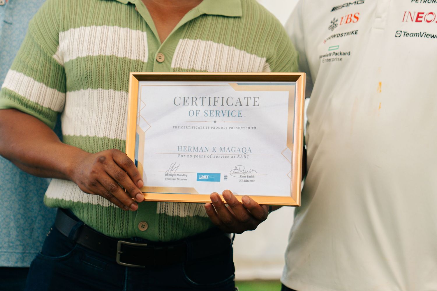 Close-up of a Certificate of Service awarded to Herman R. Maloga in a gold frame.