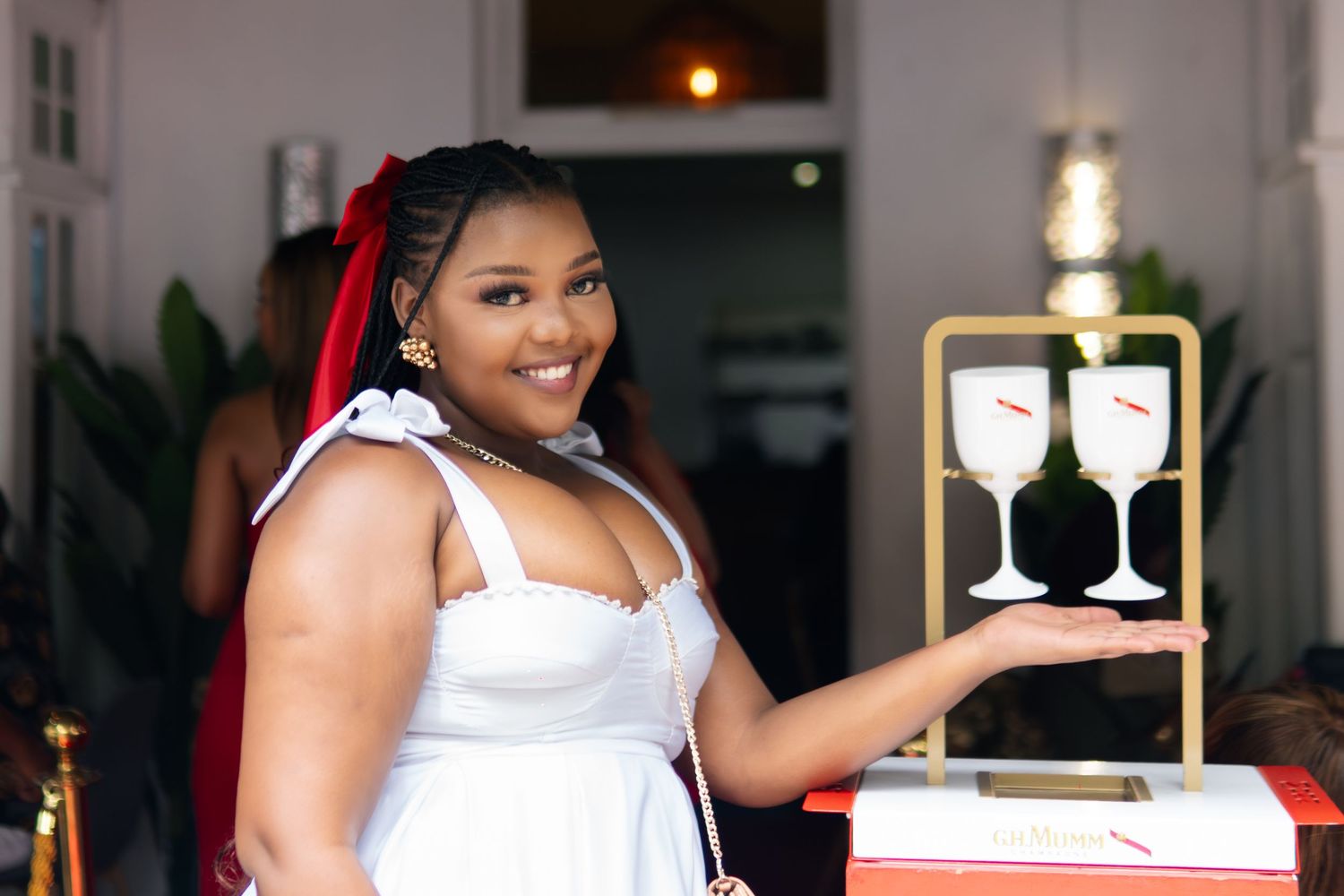 Woman in white dress posing with wine glass signage display at an elegant event.