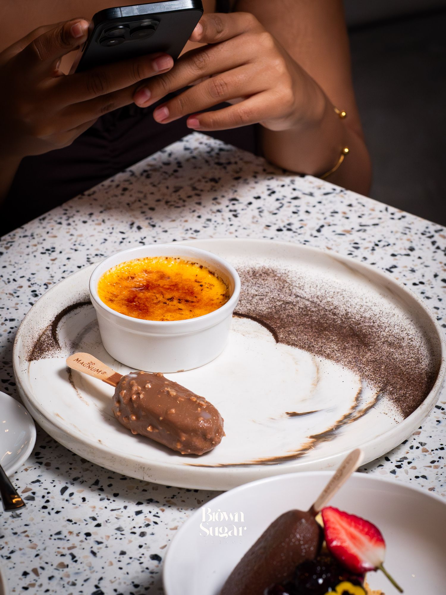 Elegant dessert plate with crème brûlée and chocolate ice cream bar dusted with cocoa powder at Brown Sugar.