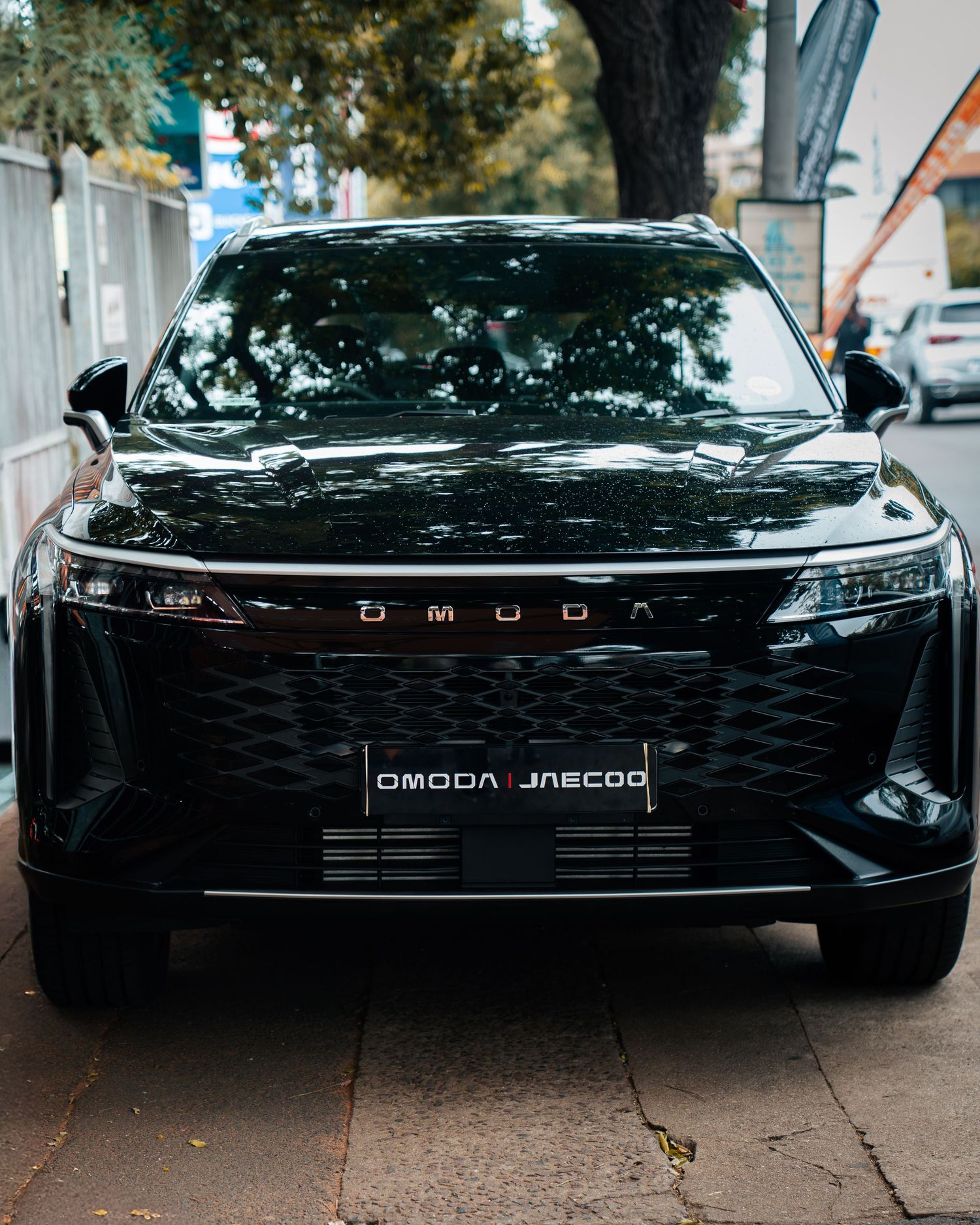 Black Omoda Jaecoo SUV front view parked on urban street, showcasing sleek grille and modern design.