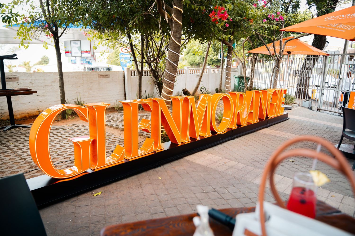 Glenmorangie whisky brand sign in bold orange letters displayed outdoors at an event venue.
