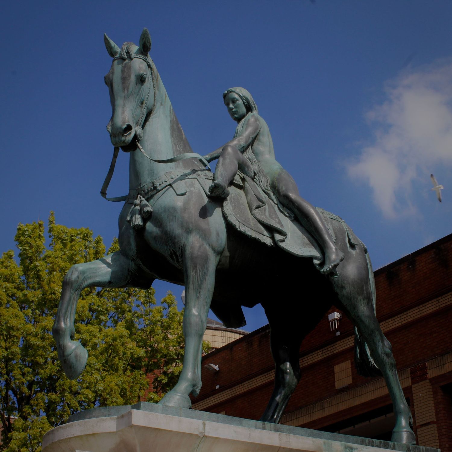 Bronze equestrian statue of Lady Godiva against blue sky in Coventry city centre.