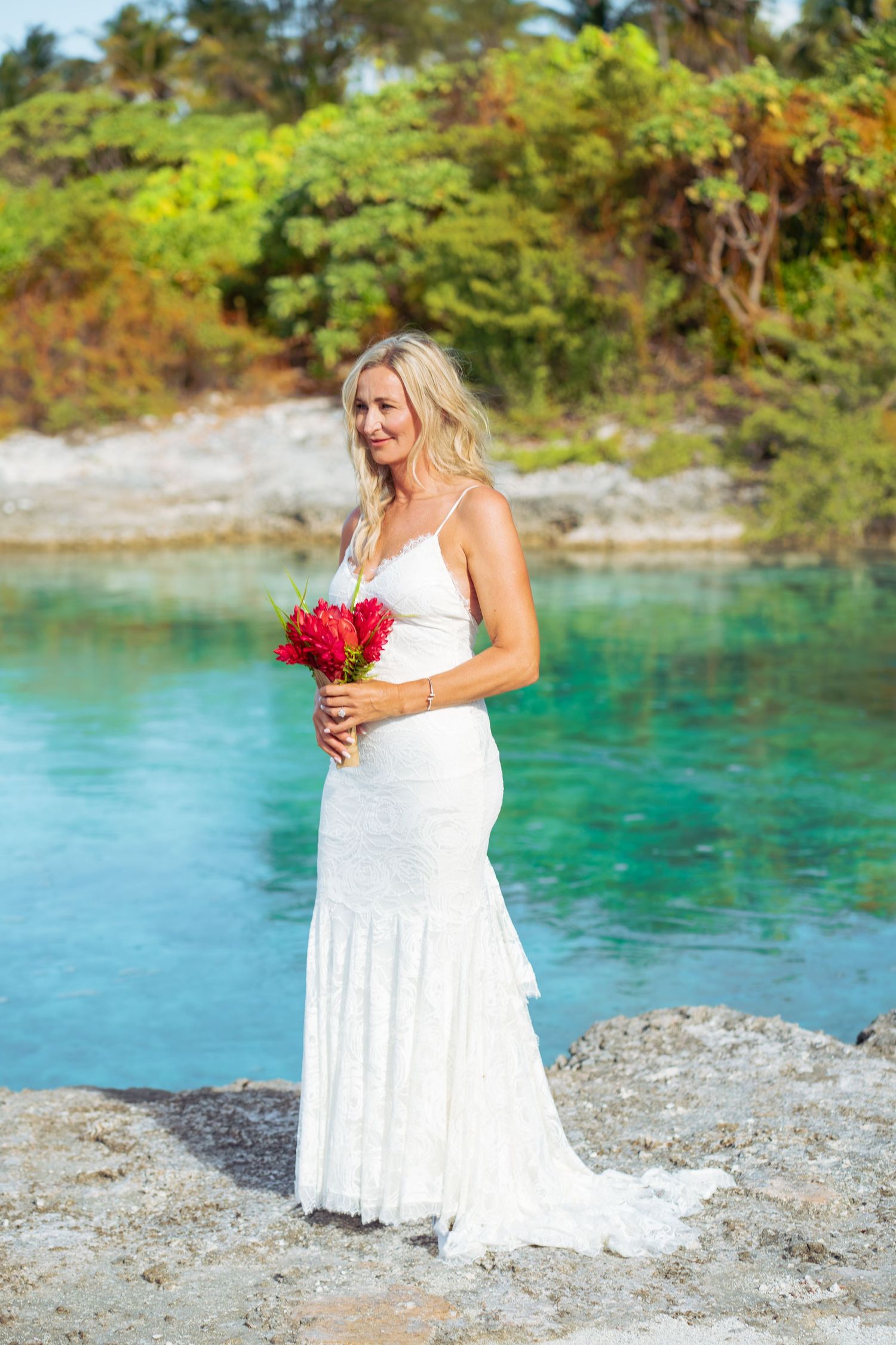 Bride holding a tropical bouquet by the Bora Bora lagoon on her wedding day