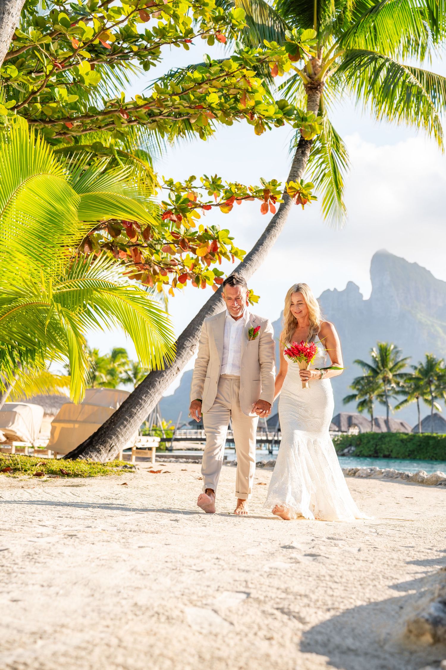 Bride and groom walking on a tropical beach during their Bora Bora destination wedding