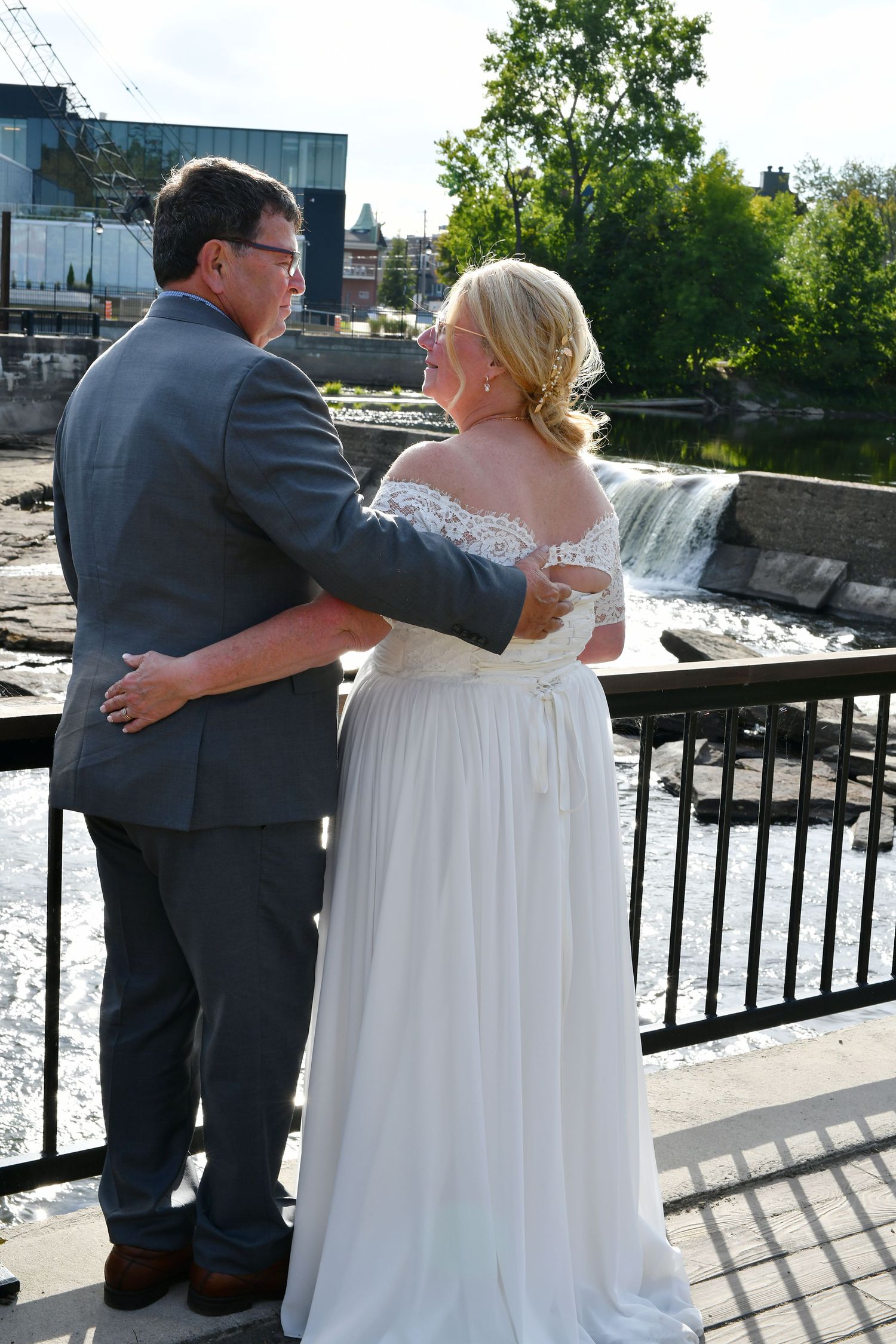 Wedding couple embraces on a bridge overlooking a beautiful waterfall on their special day.