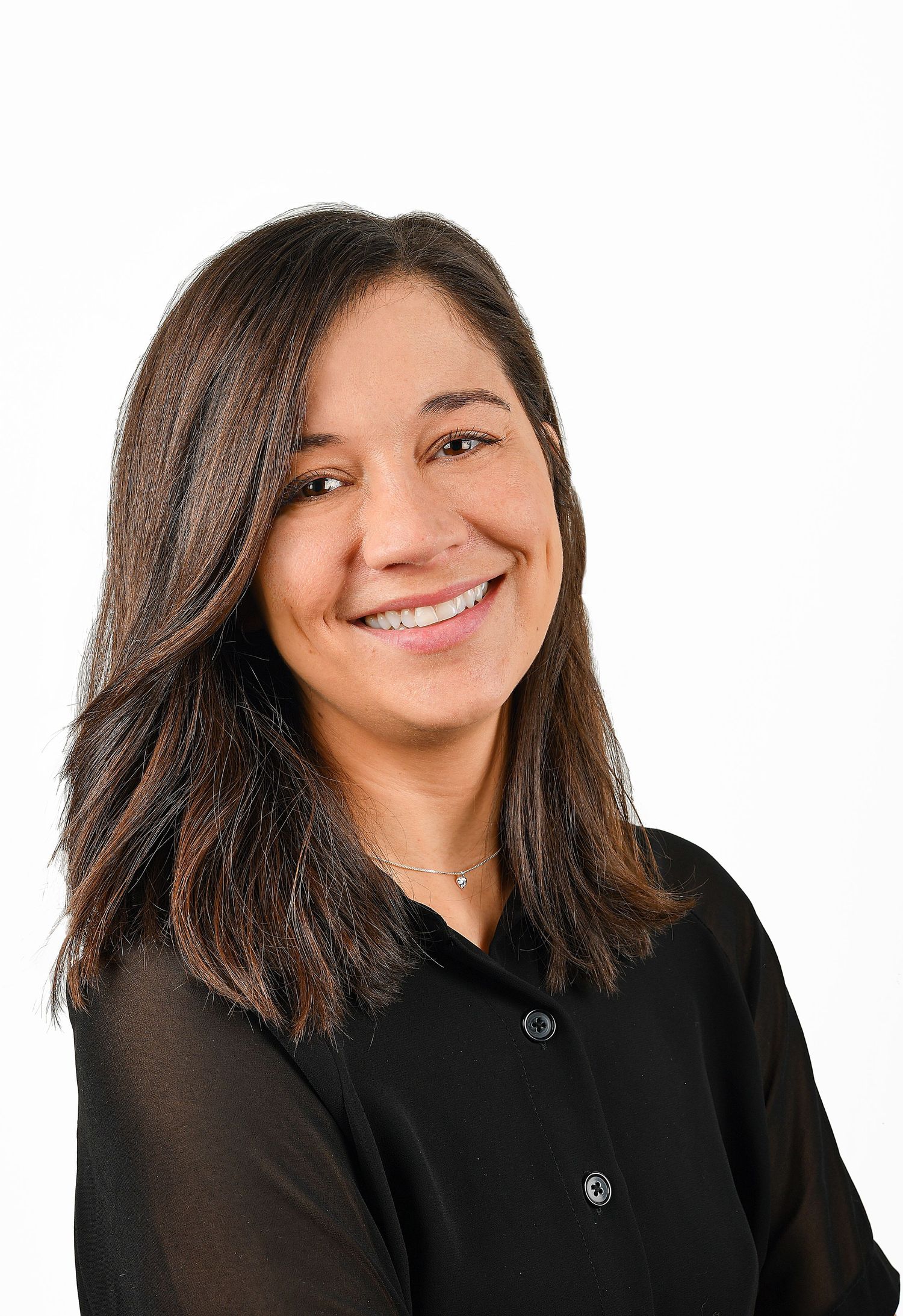 Smiling brunette woman in black blouse poses for professional headshot on white background.