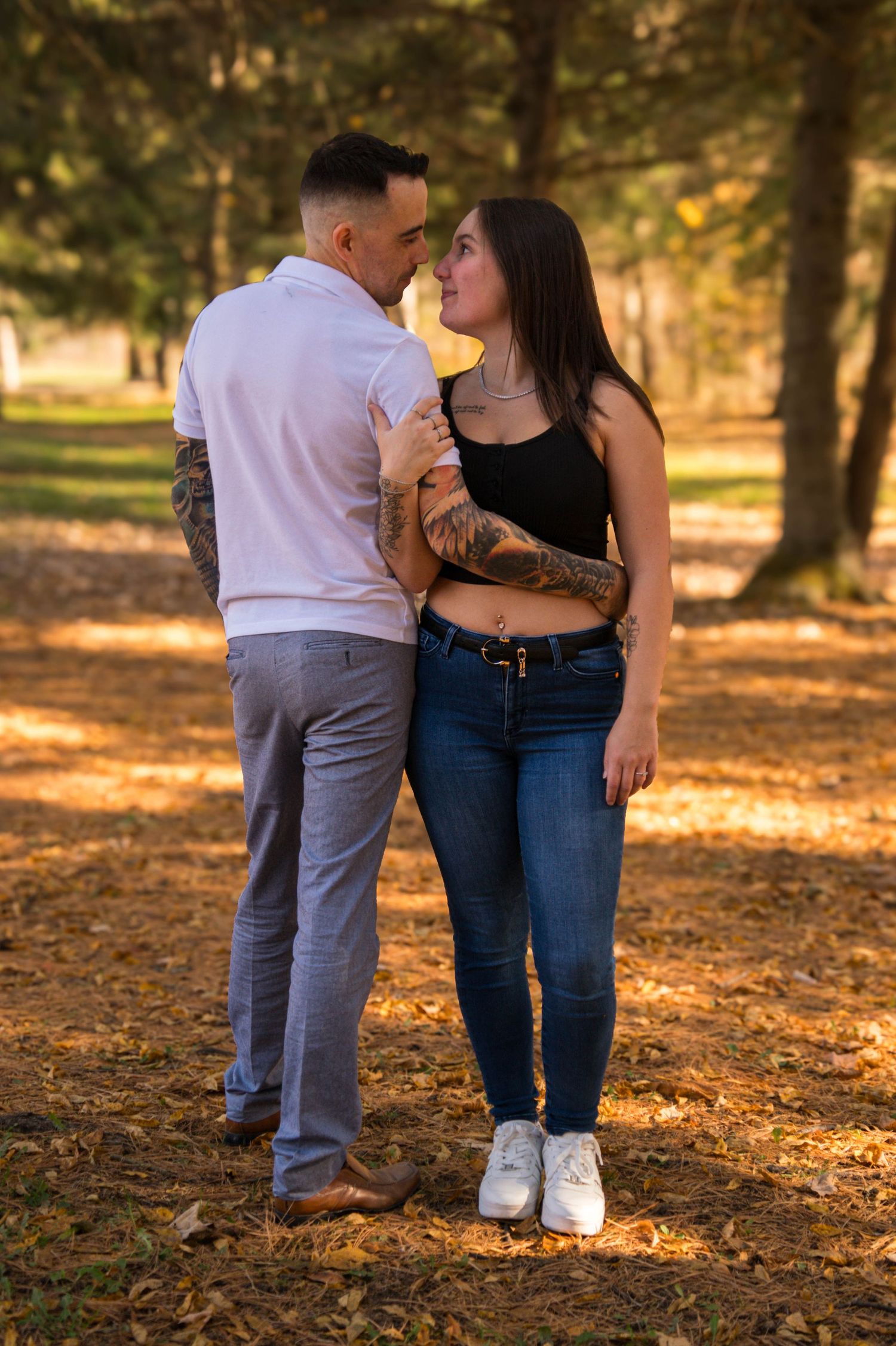 Couple sharing a romantic moment in a sunlit autumn park during an outdoor engagement photo session.
