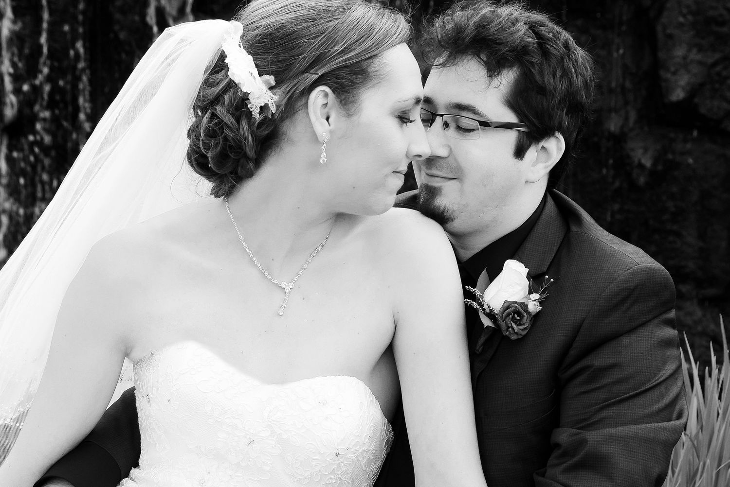 Black and white romantic portrait of a bride and groom sharing a tender moment close together.
