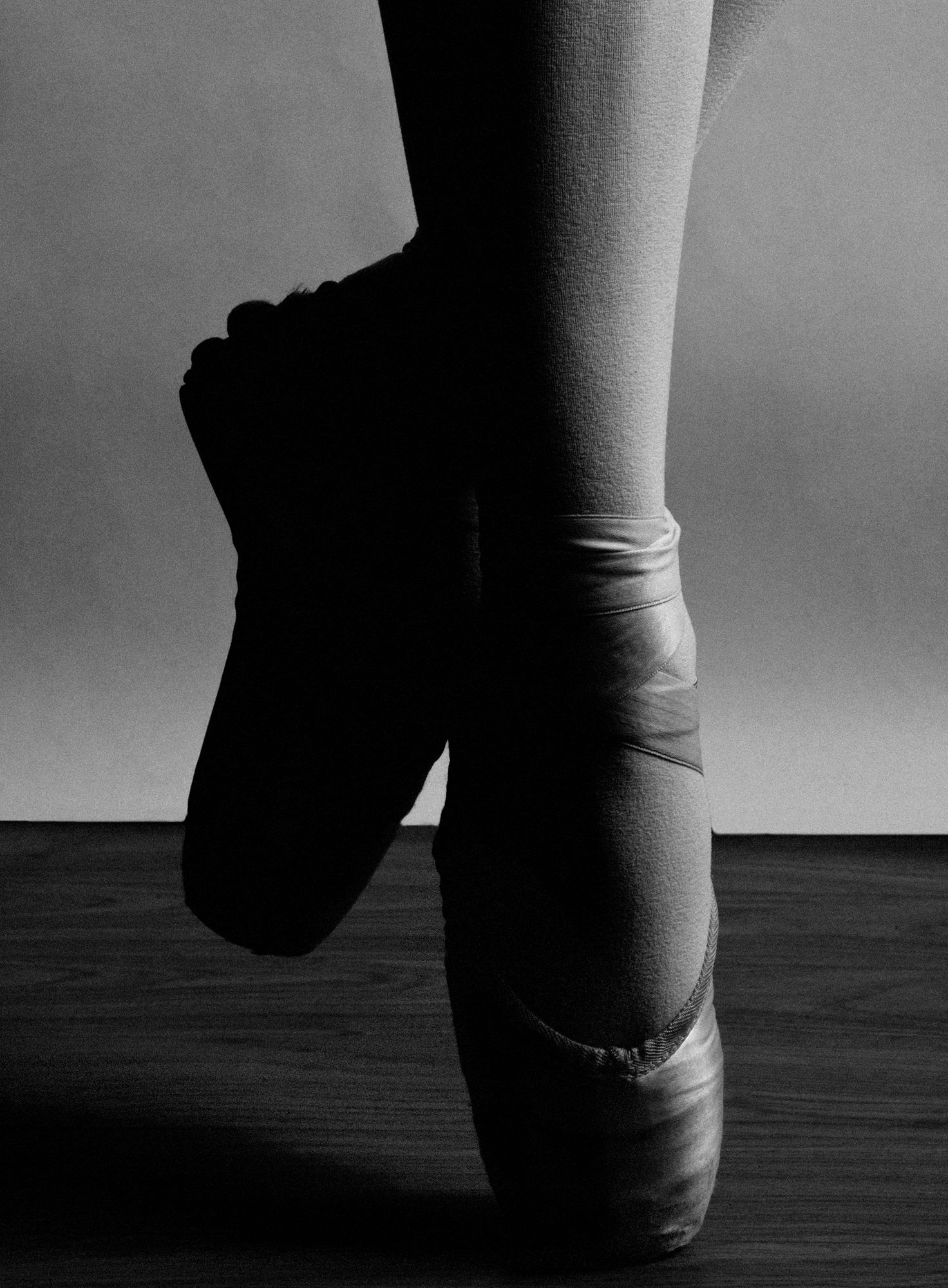 Close-up black and white photo of ballet dancer feet in worn pointe shoes.