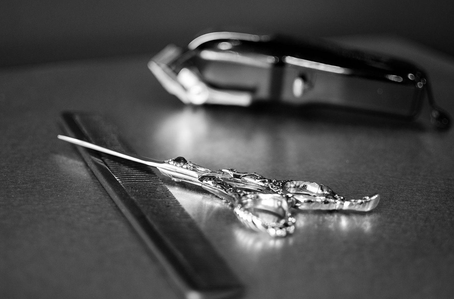 Black and white close-up of decorative scissors, ruler, and hair clipper on table.