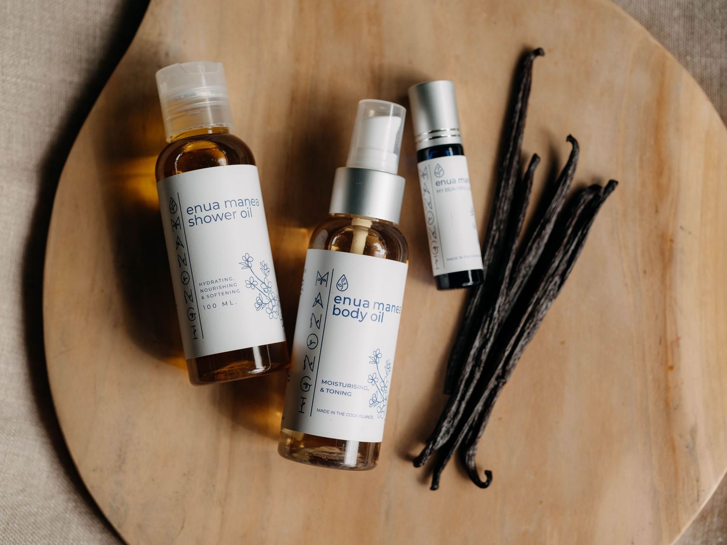 Four Venus Maven skincare products with vanilla beans on a wooden tray, including shower gel, body oil, and serums.