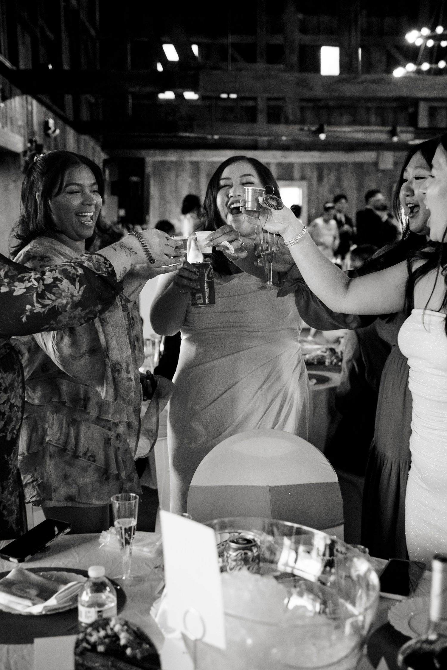 black and white photo of a group of women holding up glasses in cheers.