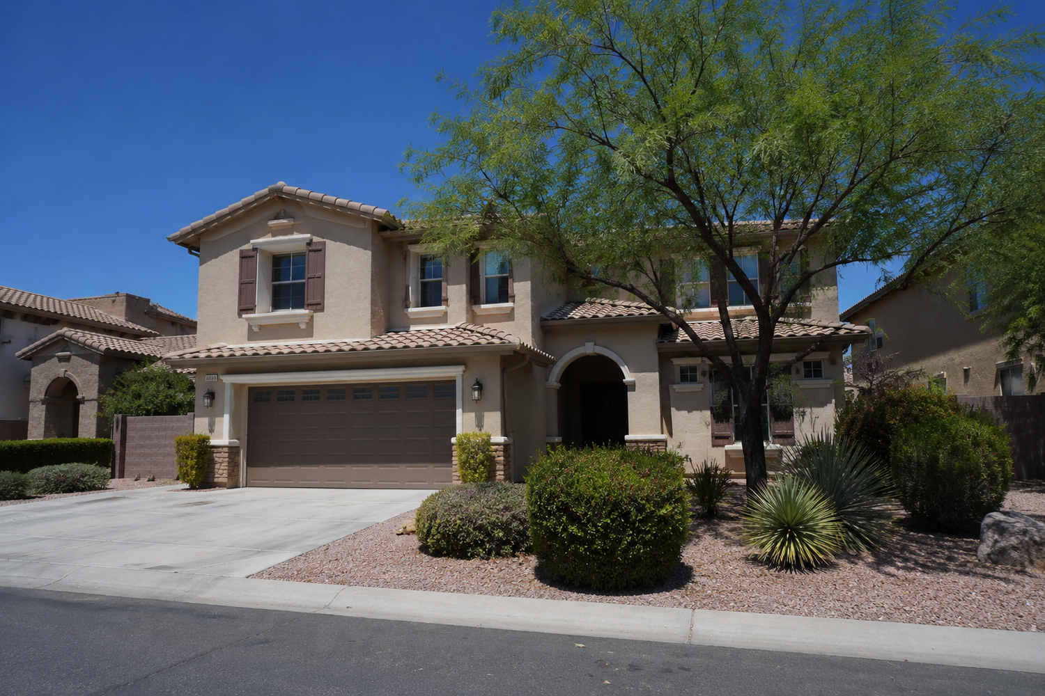 Two-story tan stucco home with desert landscaping and two-car garage in New Jersey..