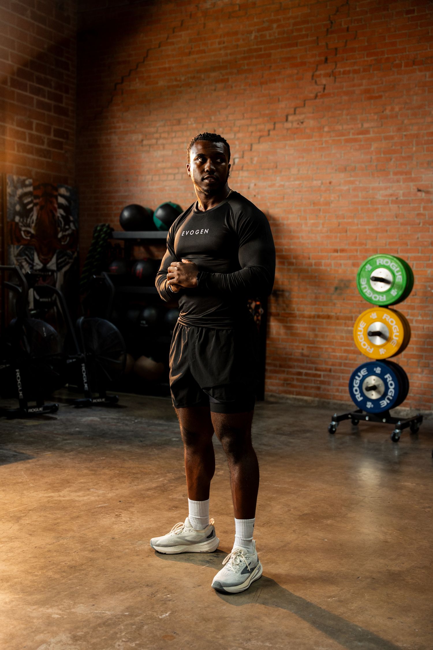 Fit man in black Evogen long sleeve shirt posing in brick gym.