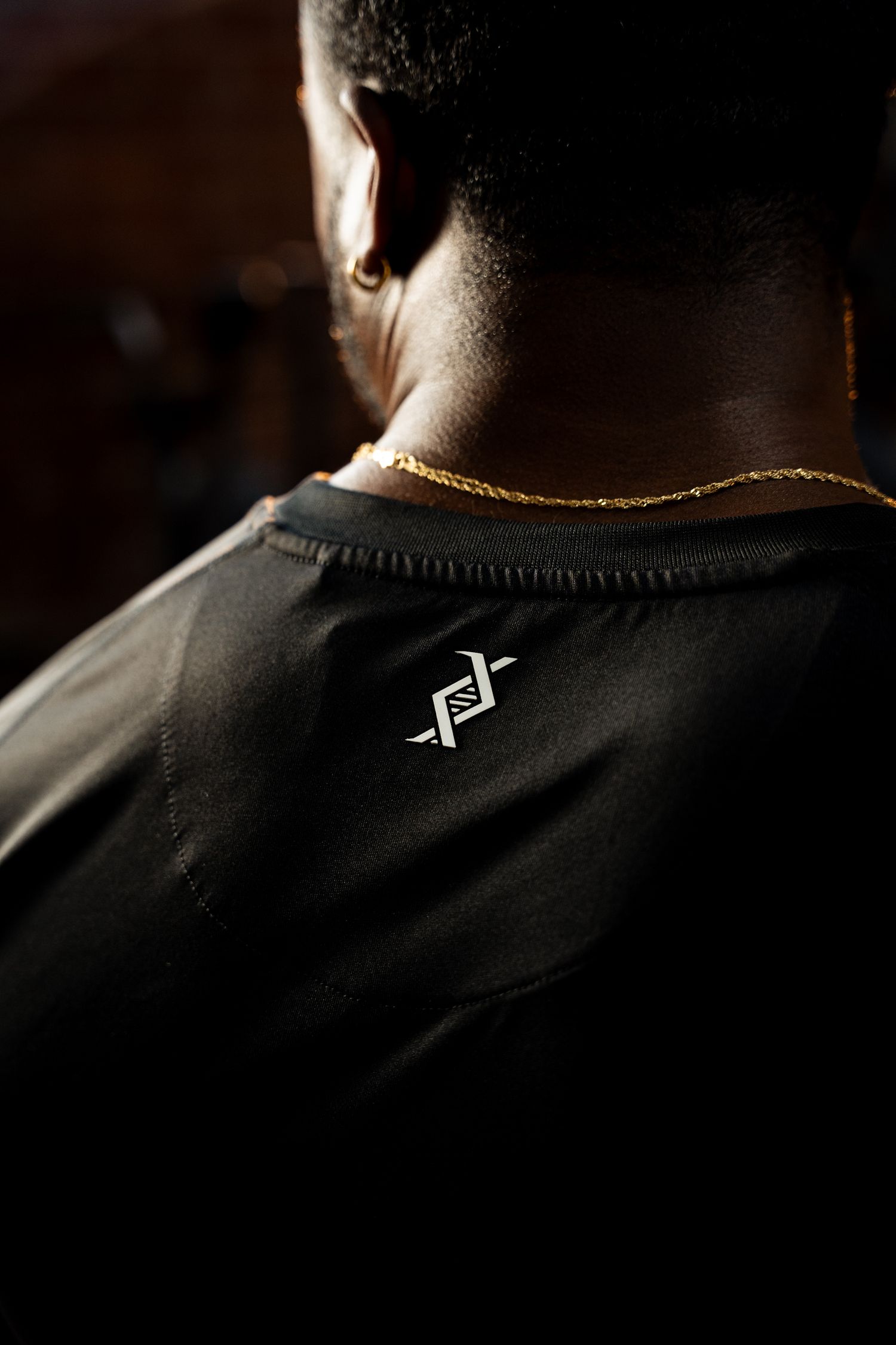 Back view of man wearing black Evogen branded shirt with gold chain.