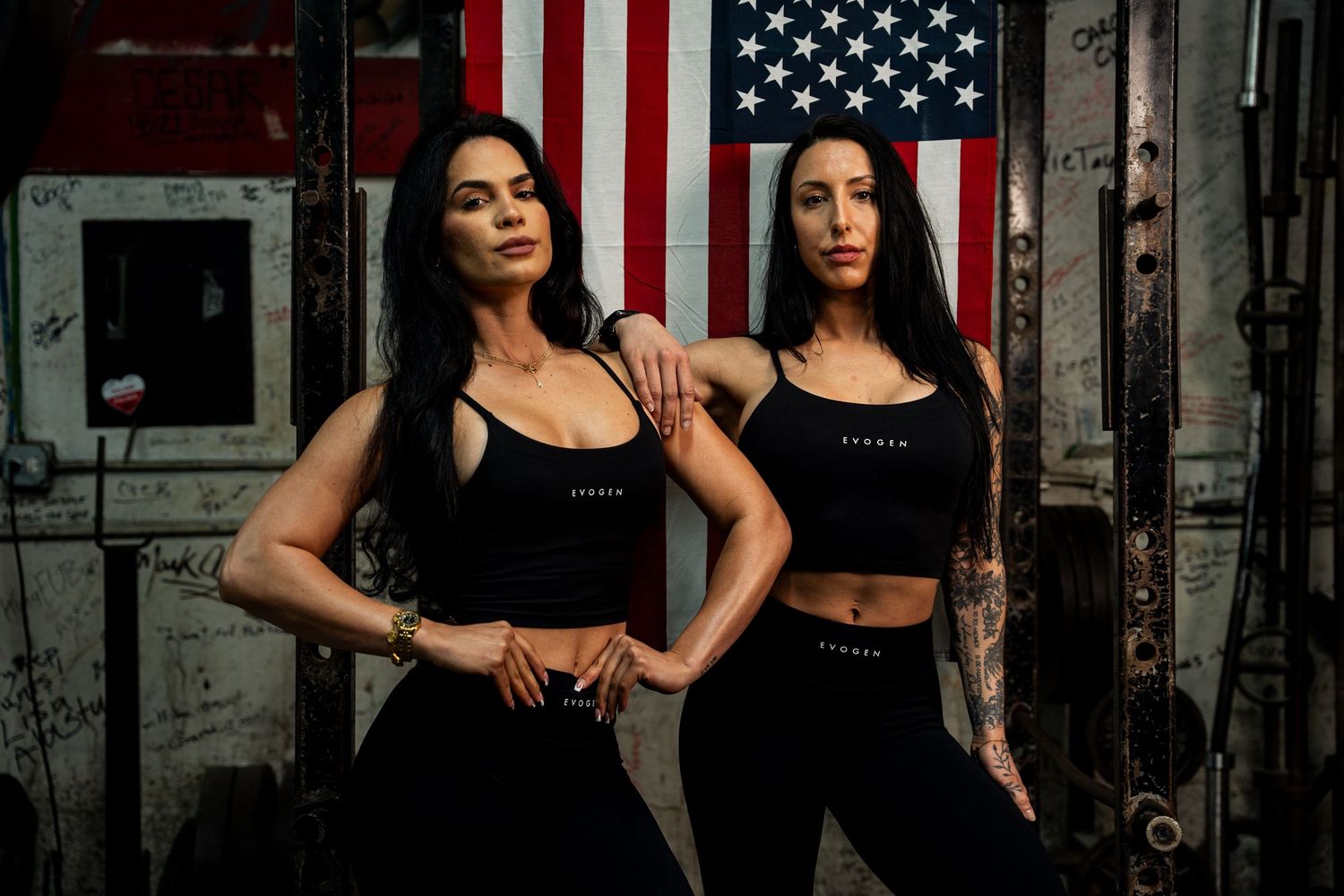 Two athletic women in black Evogen activewear pose together in front of an American flag.