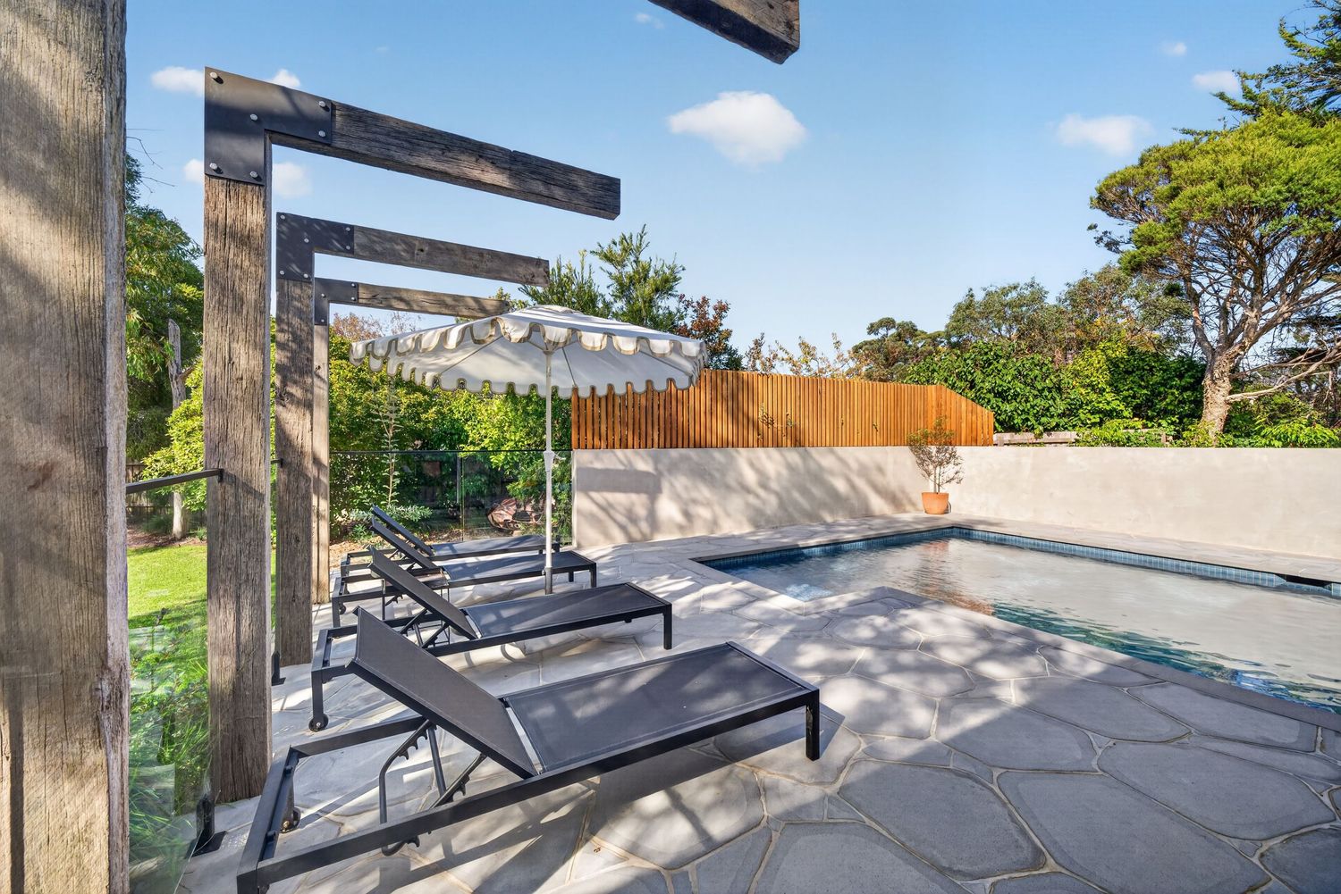 Image of a feature timber structure beside a swimming pool, highlighting natural wood detailing, outdoor architectural design