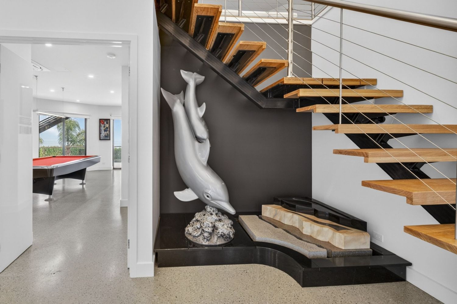 Entryway featuring a dolphin statue, highlighting decorative sculpture, architectural styling, and a welcoming interior focal point.