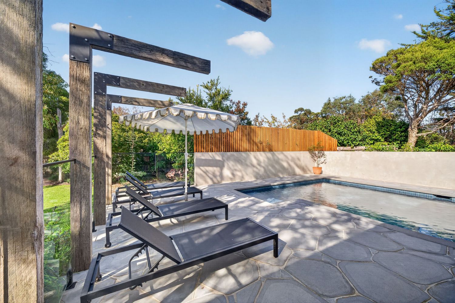 Image of a feature timber structure beside a swimming pool, highlighting natural wood detailing, outdoor architectural design