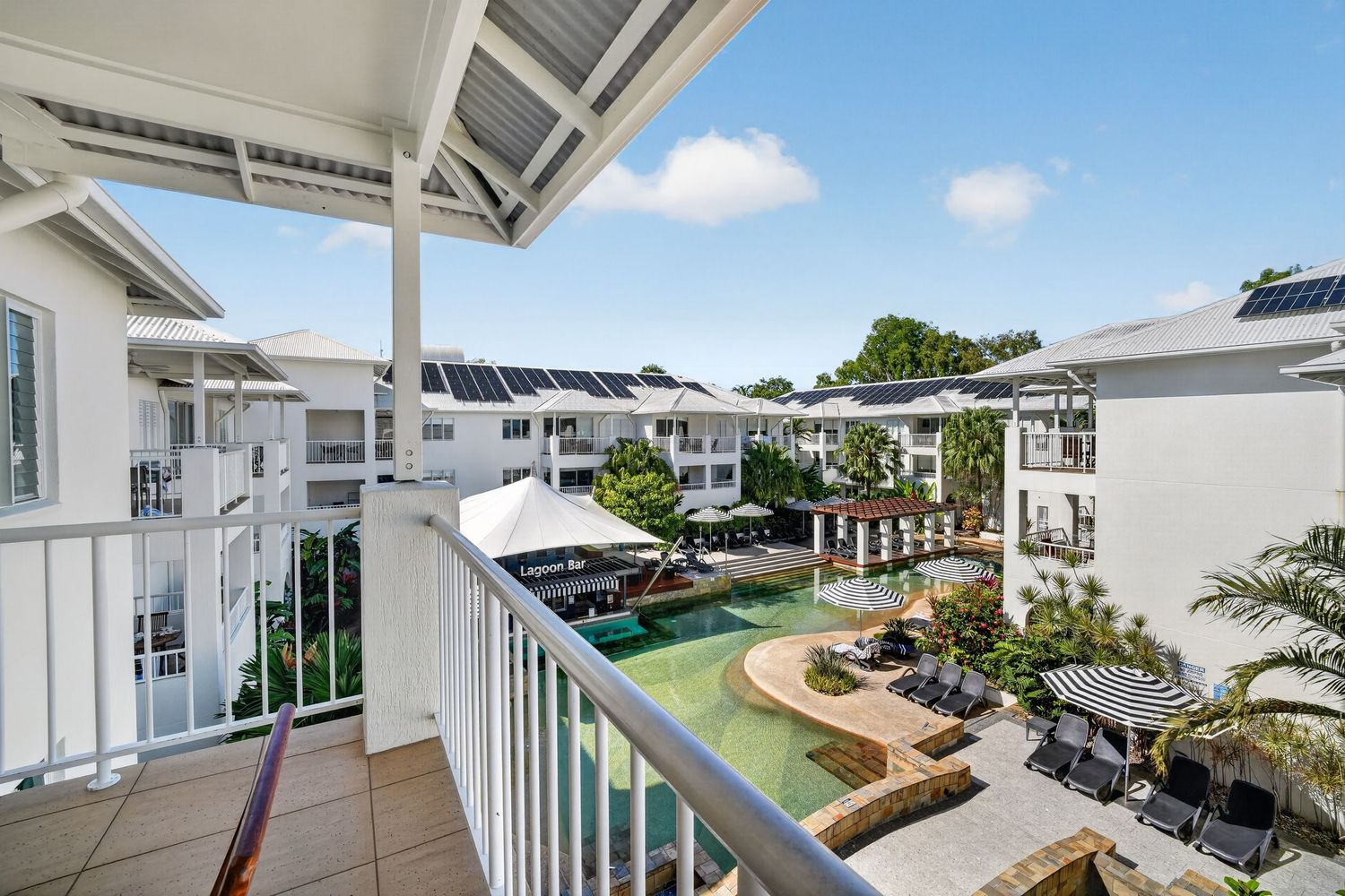 View of lagoon pool from holiday apartment balcony, showcasing elevated perspective,resort-style water views, and relaxed coastal atmosphere