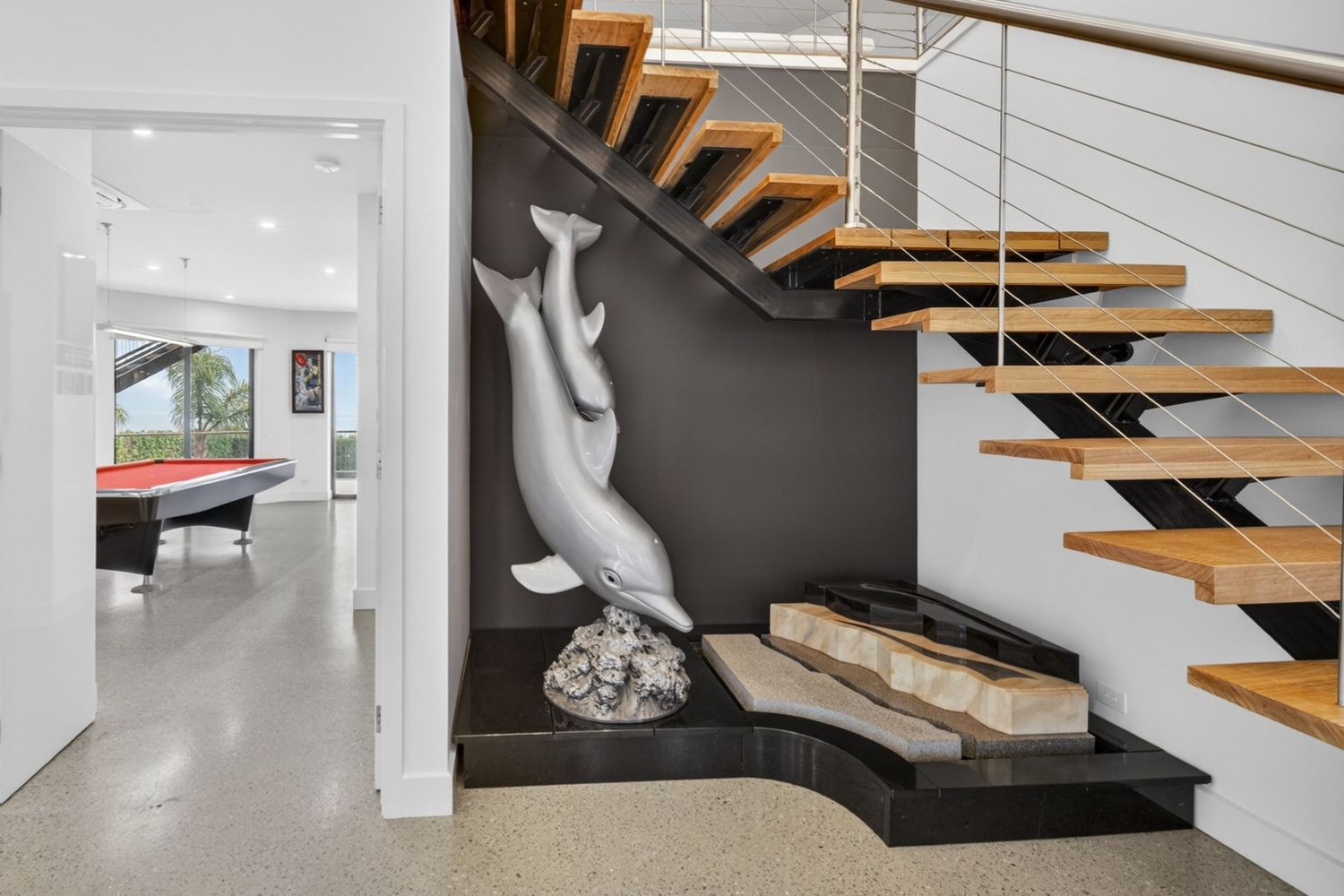 Entryway featuring a dolphin statue, highlighting decorative sculpture, architectural styling, and a welcoming interior focal point.