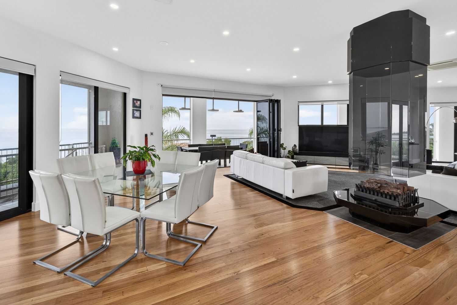 Living & dining area featuring a glass roof and suspended fireplace, highlighting open-plan design, architectural detailing & natural light