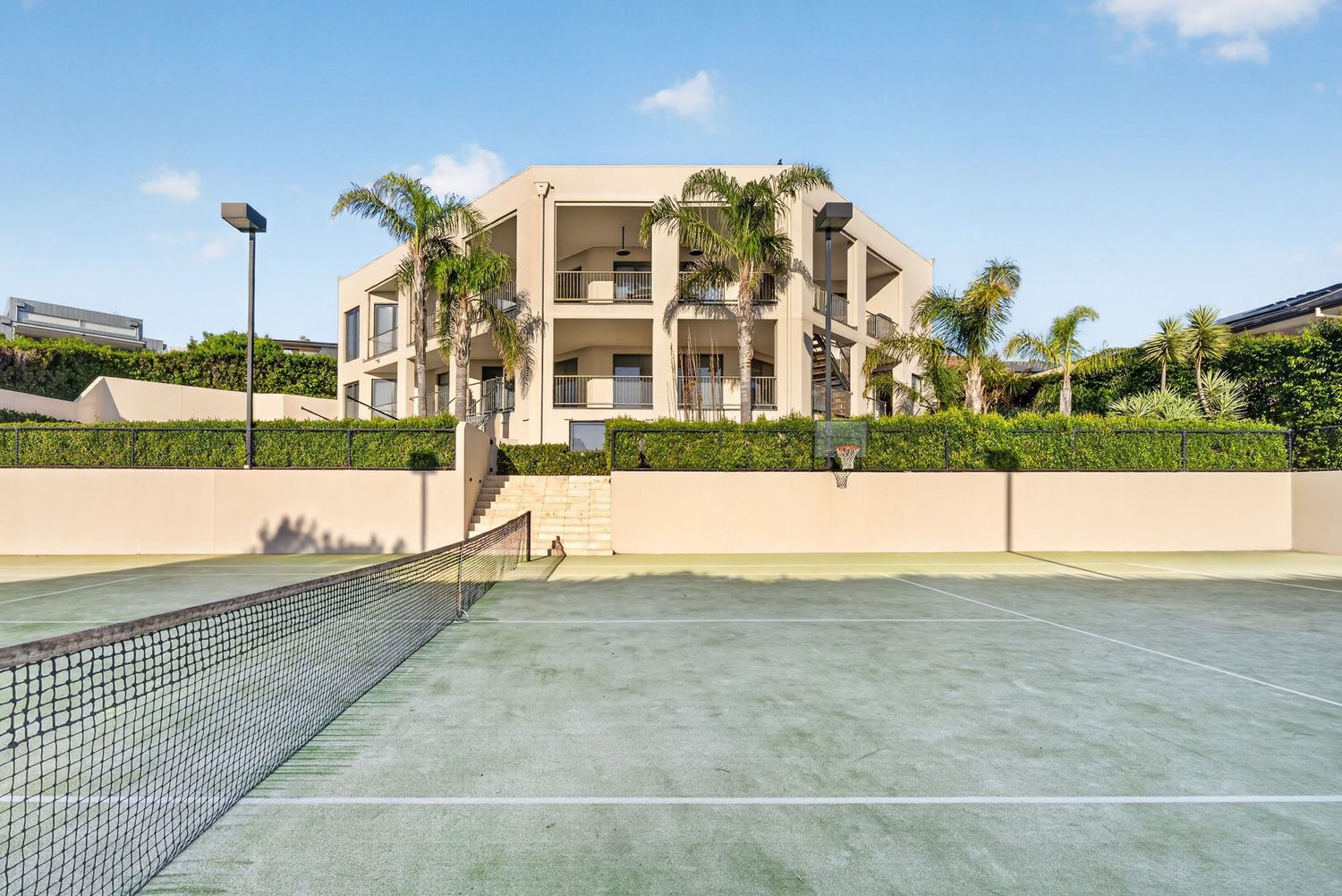 Exterior shot of a prestige home in Mount Eliza captured from the tennis court, highlighting expansive landscaping, architectural design