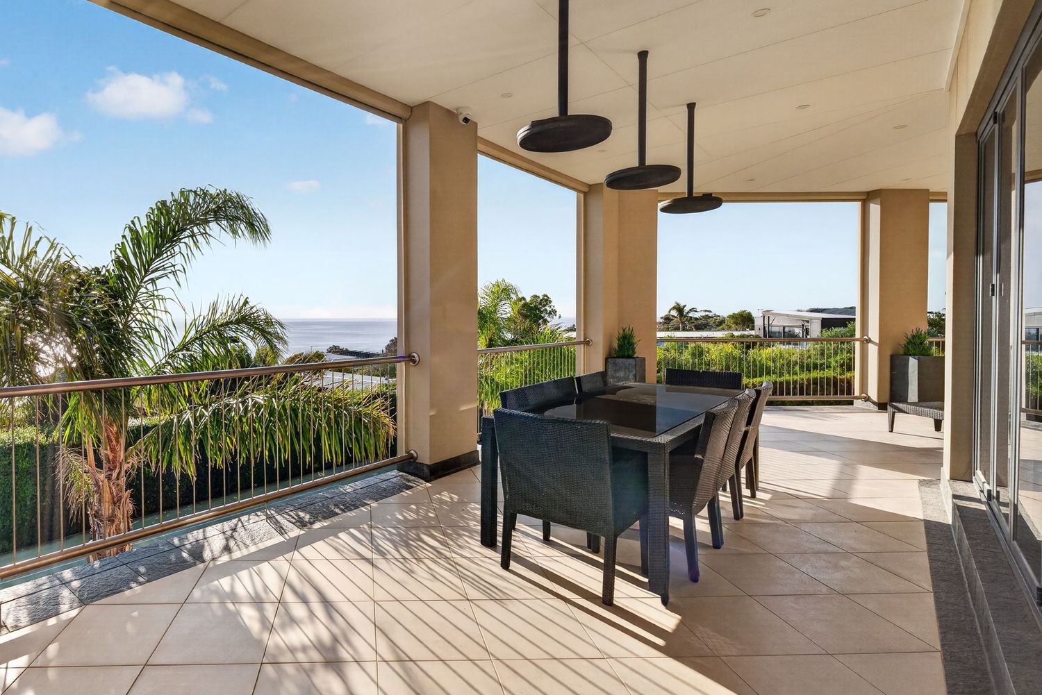 Outdoor dining on a balcony, featuring a styled table setting, open-air living, and elevated views in a relaxed coastal setting.