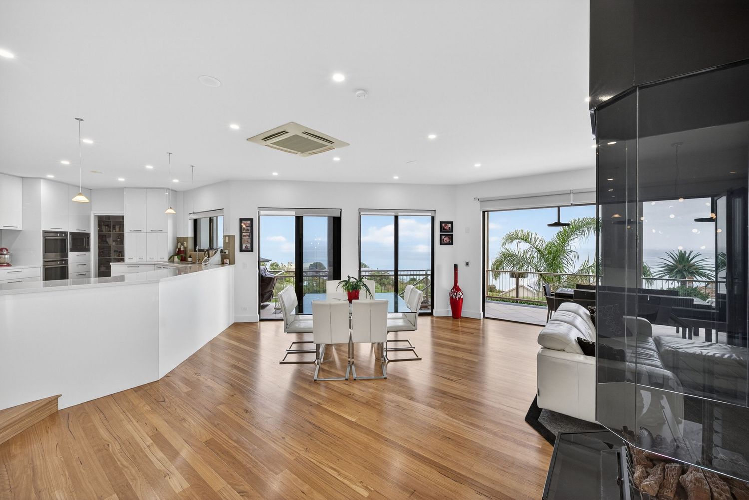 Kitchen & dining area featuring a glass roof and suspended fireplace, highlighting open-plan design, architectural detailing & natural light