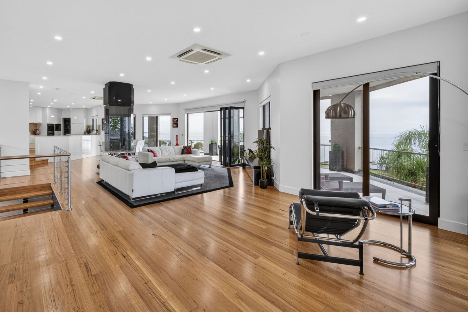 Wide angle shot of living, dining, kitchen, and balcony, showcasing open-plan design, seamless indoor-outdoor flow