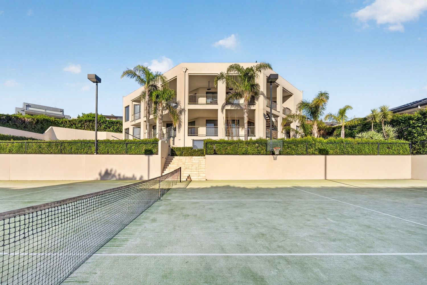 Exterior shot of a prestige home in Mount Eliza captured from the tennis court, highlighting expansive landscaping, architectural design