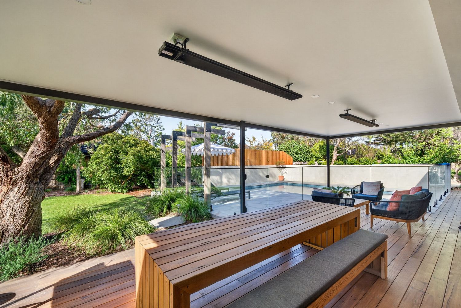 Outdoor dining area overlooking a swimming pool, capturing seamless indoor-outdoor living, landscaped surroundings