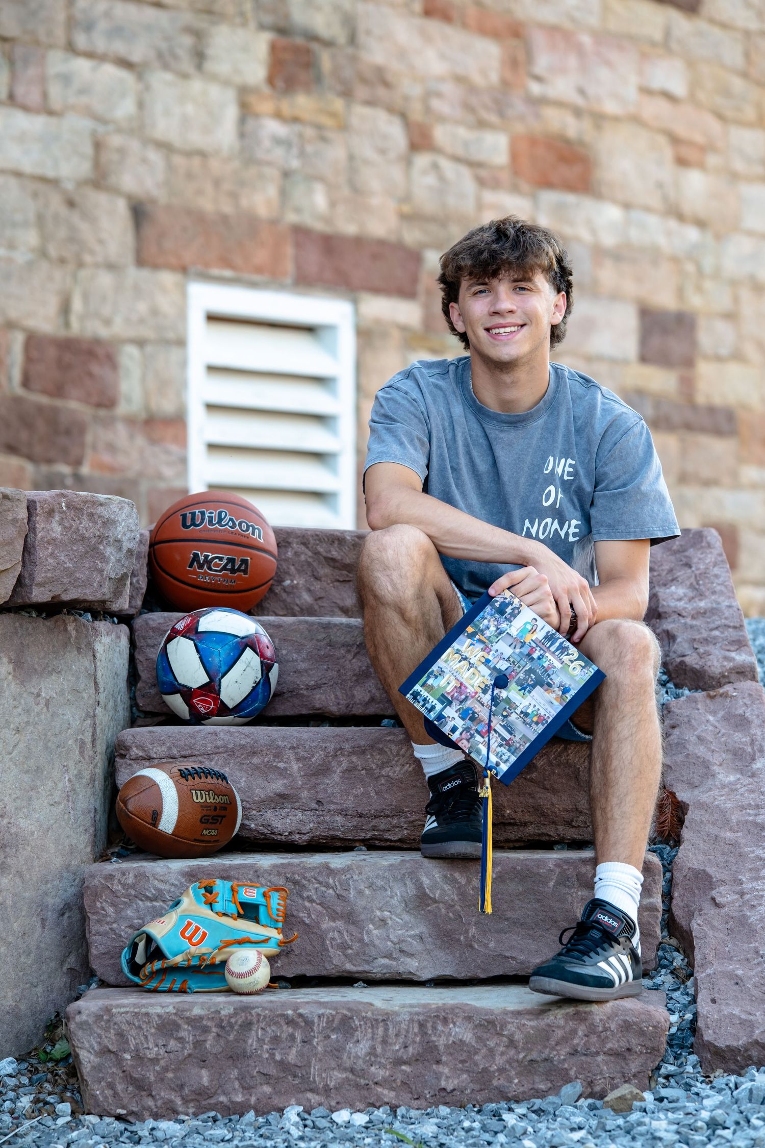 senior boy holding graduation cap with sports memorabilia