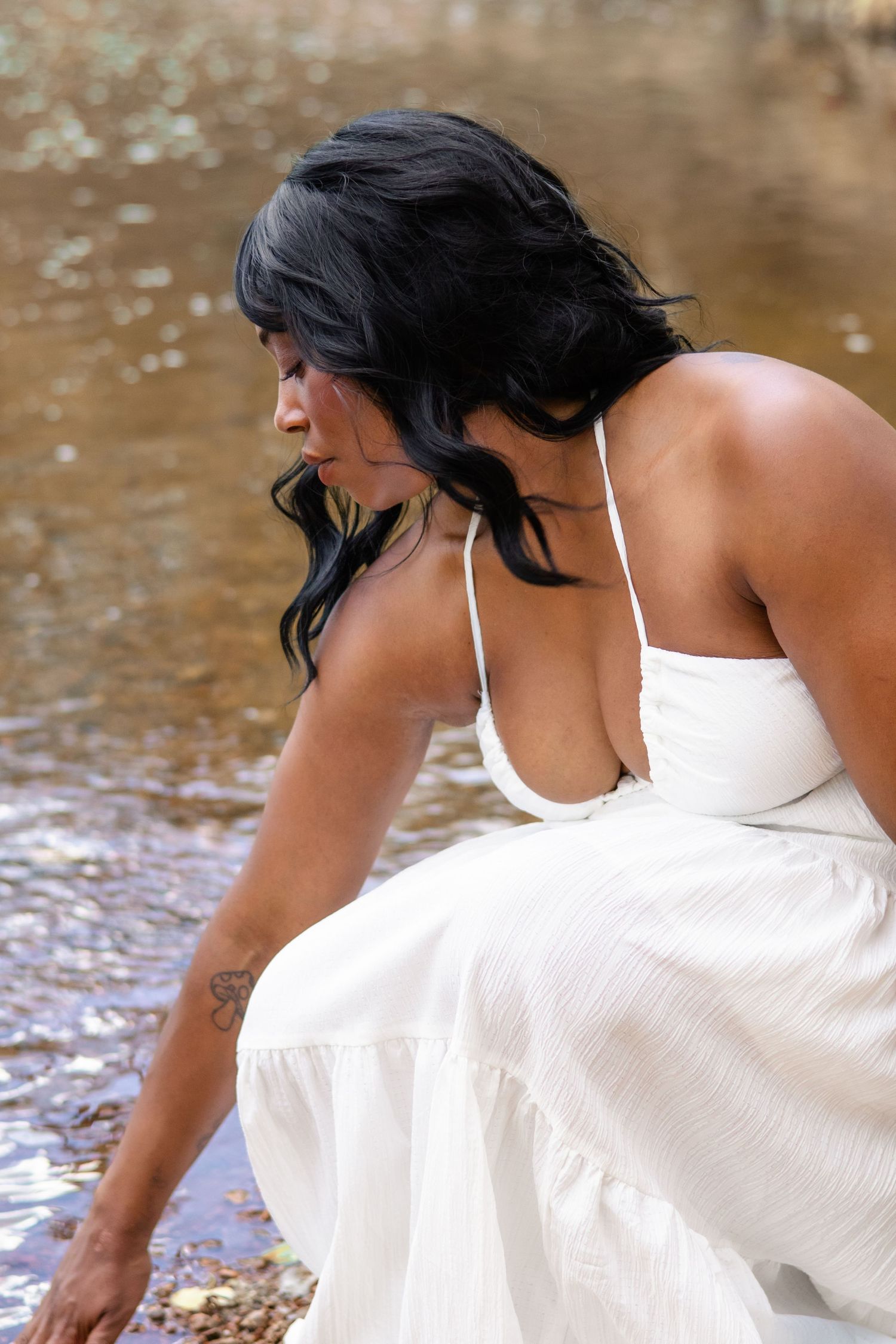 A woman with black hair in a white sundress near a peaceful woodland stream at Chatfield Res in Jefferson County, Colorado.