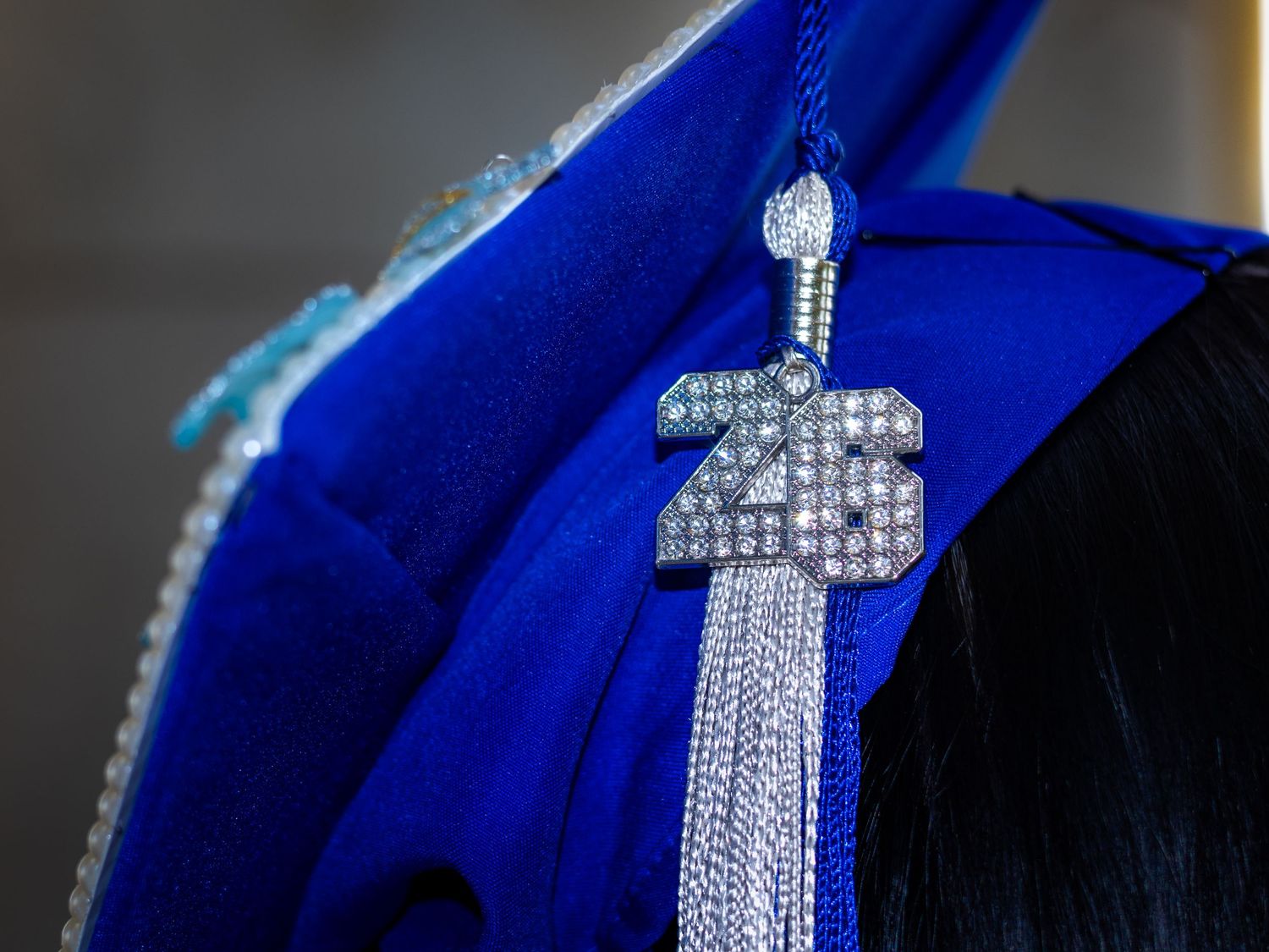 Close-up of sparkly rhinestone 2025 tassel charm on blue graduation cap in Littleton, Colorado.